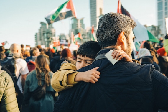 A man hugs a young boy in a crowd of people