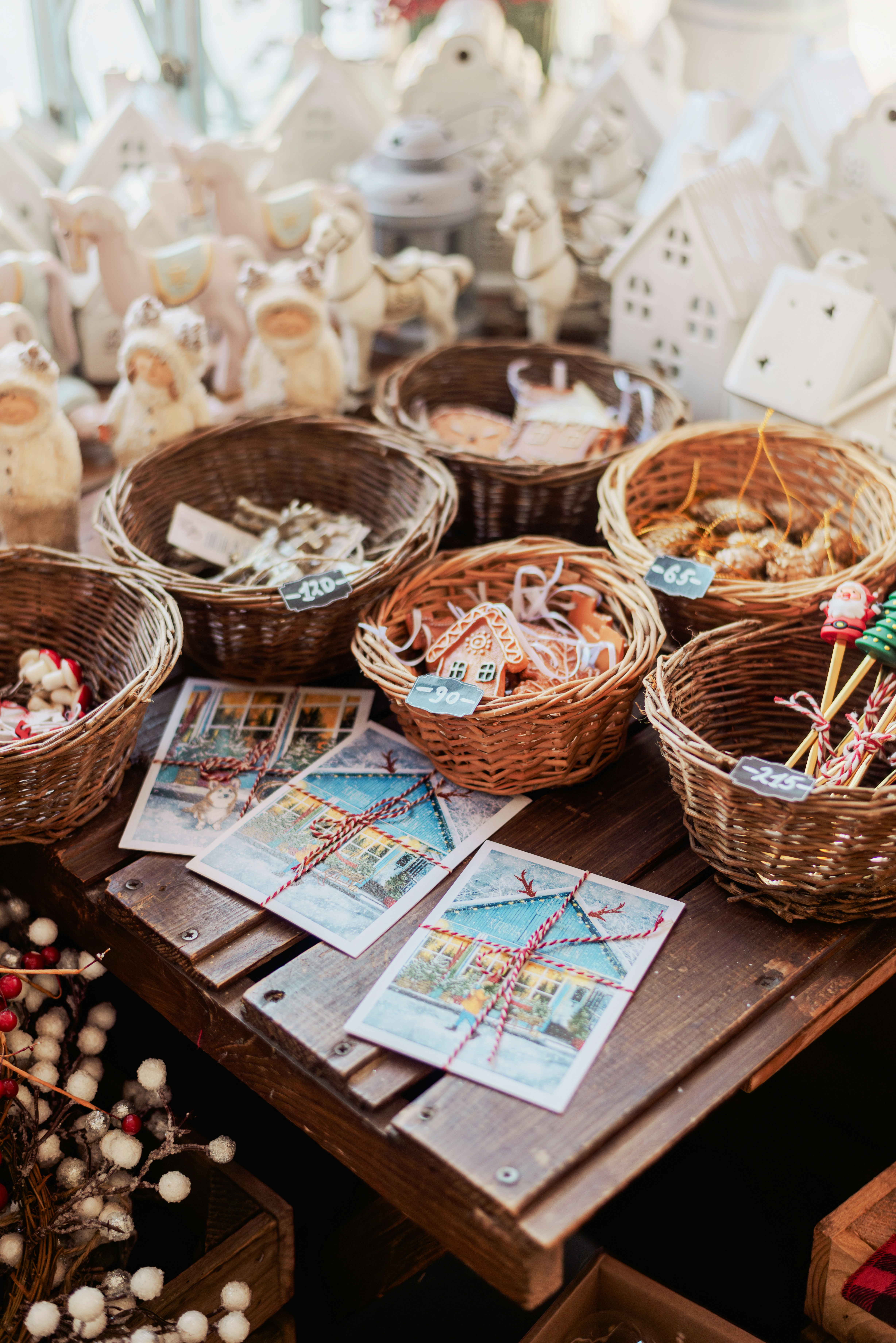 Wicker gift basket filled with assorted holiday treats, red ribbon, and festive decorations on wooden table