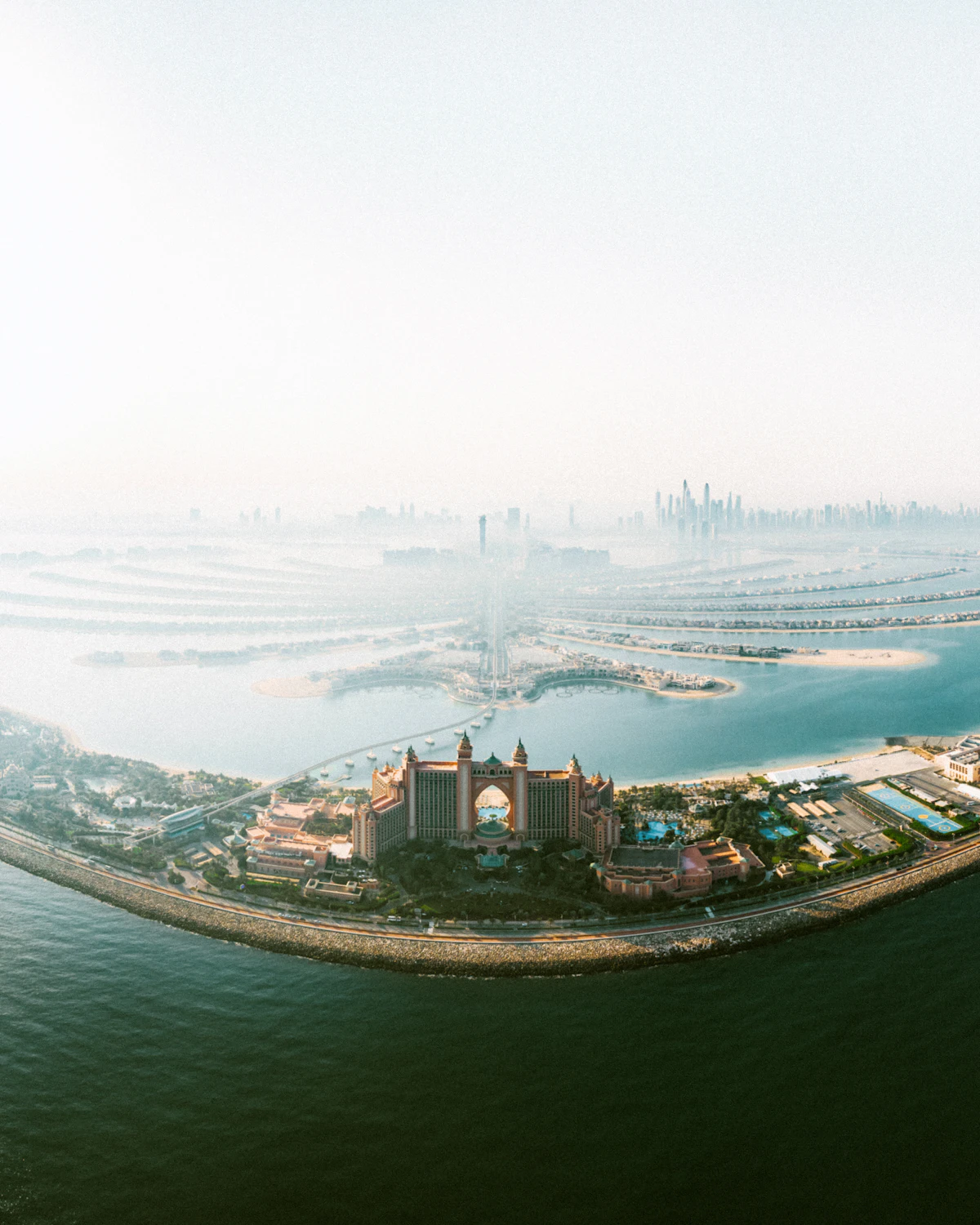 Palm Jumeirah and Atlantis seen from high above in the morning haze, the Dubai skyline behind