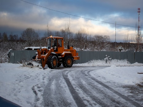 A tractor is driving down a snowy road