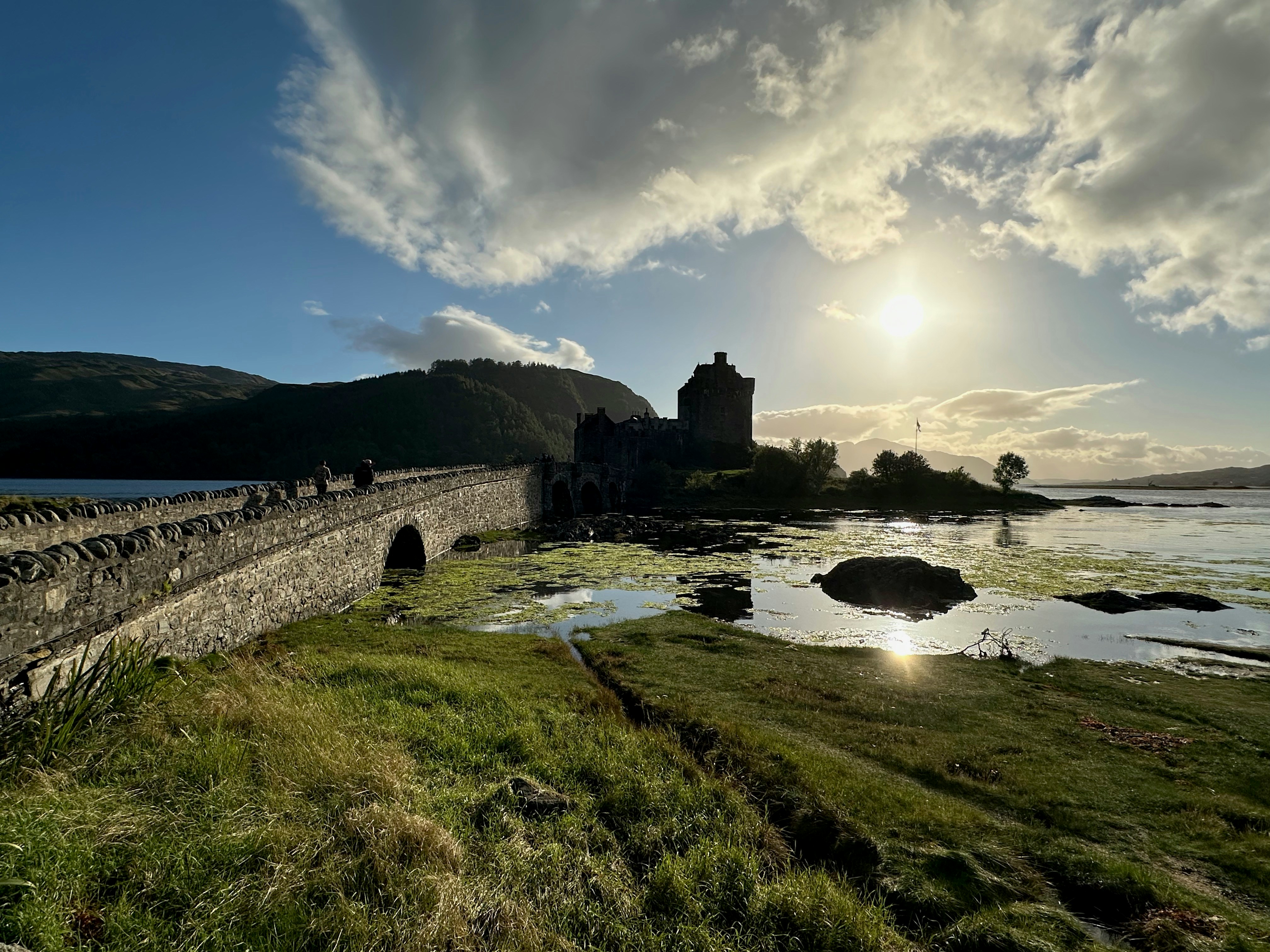 Il sole splende sull'acqua e su un ponte di pietra