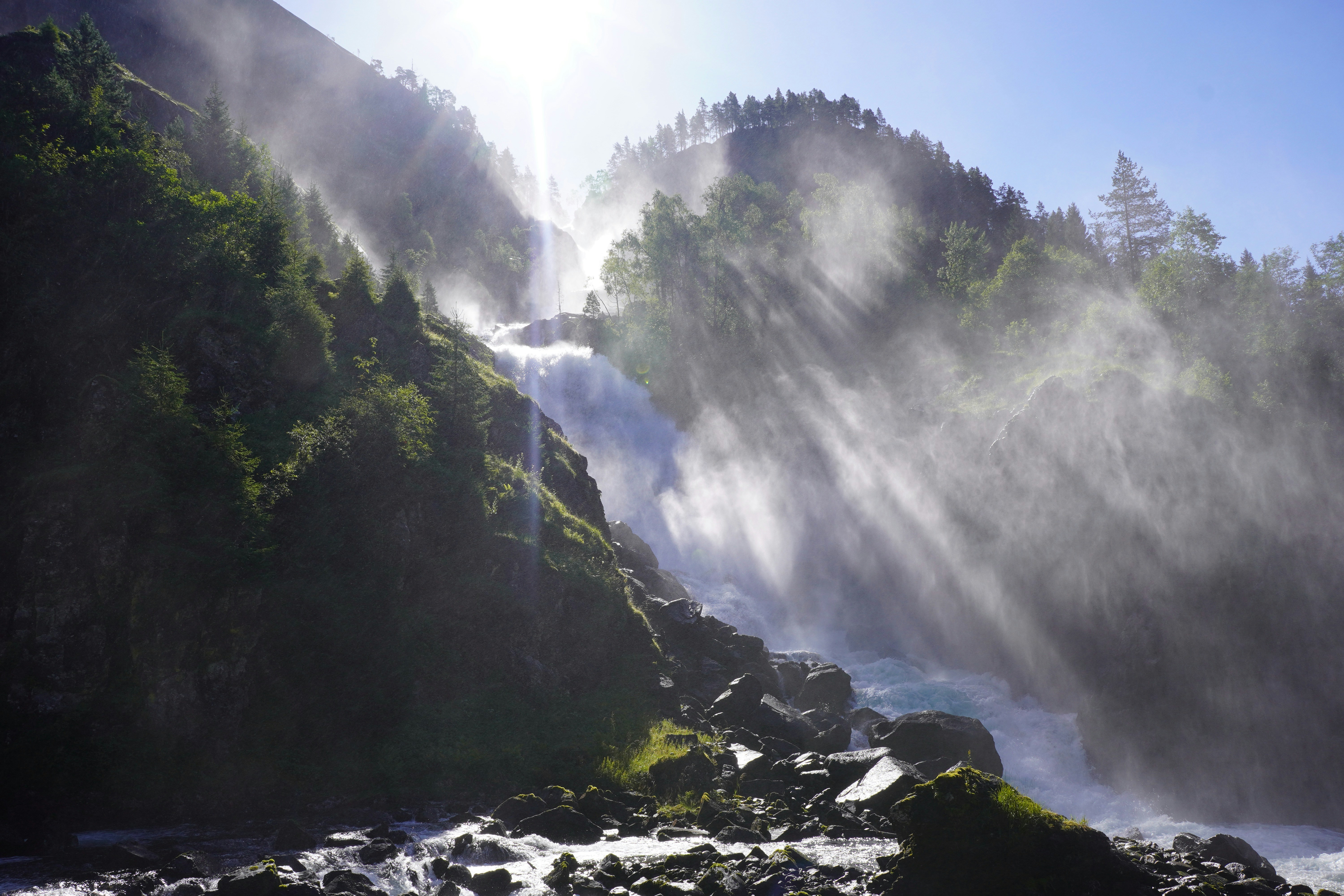 The sun shines brightly on a mountain stream