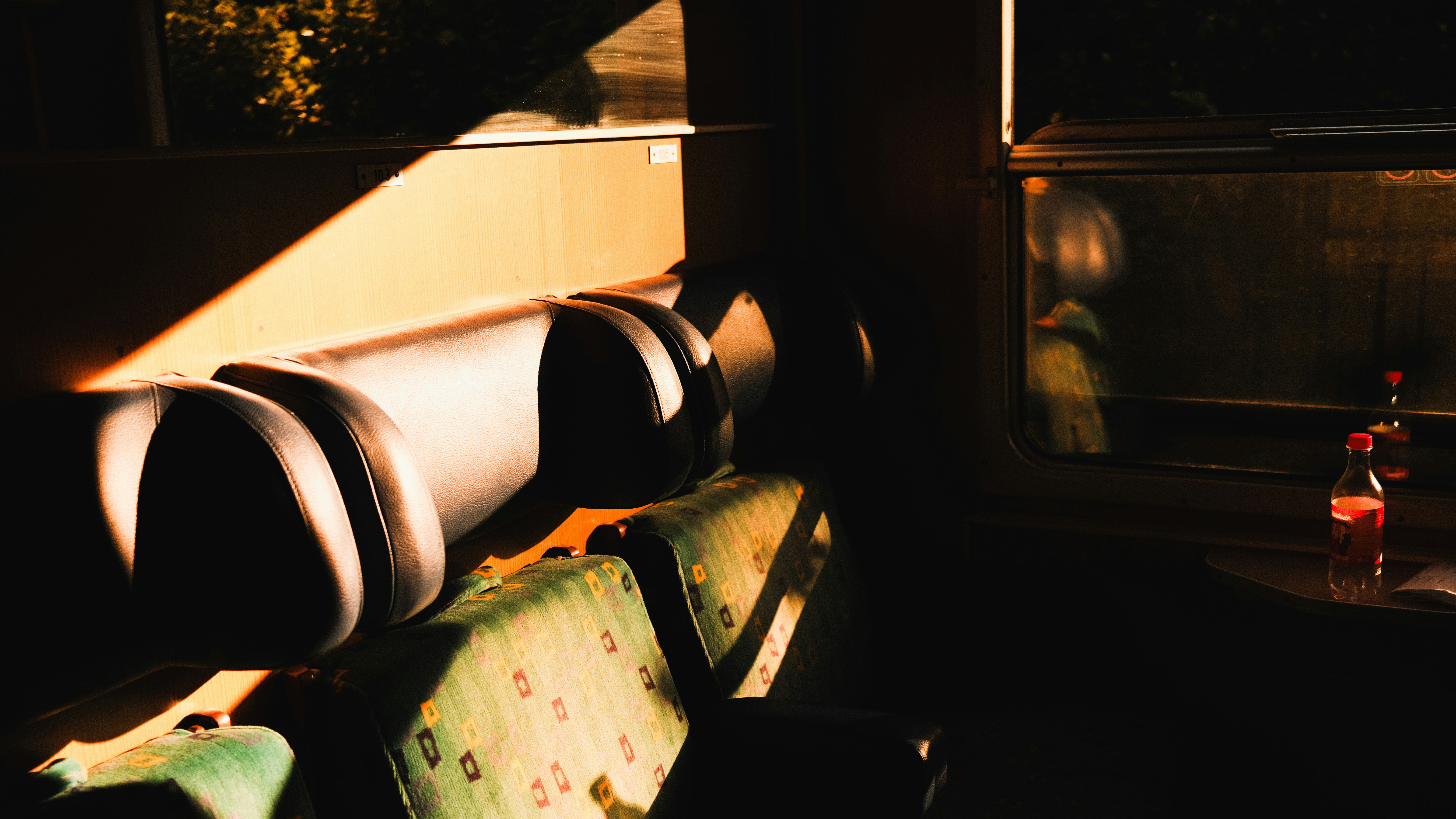 A close-up shot of a moldy bread piece, clearly showing green or black fungus, lying on a disposable food tray inside a train compartment. A hand might be pointing at the mold.