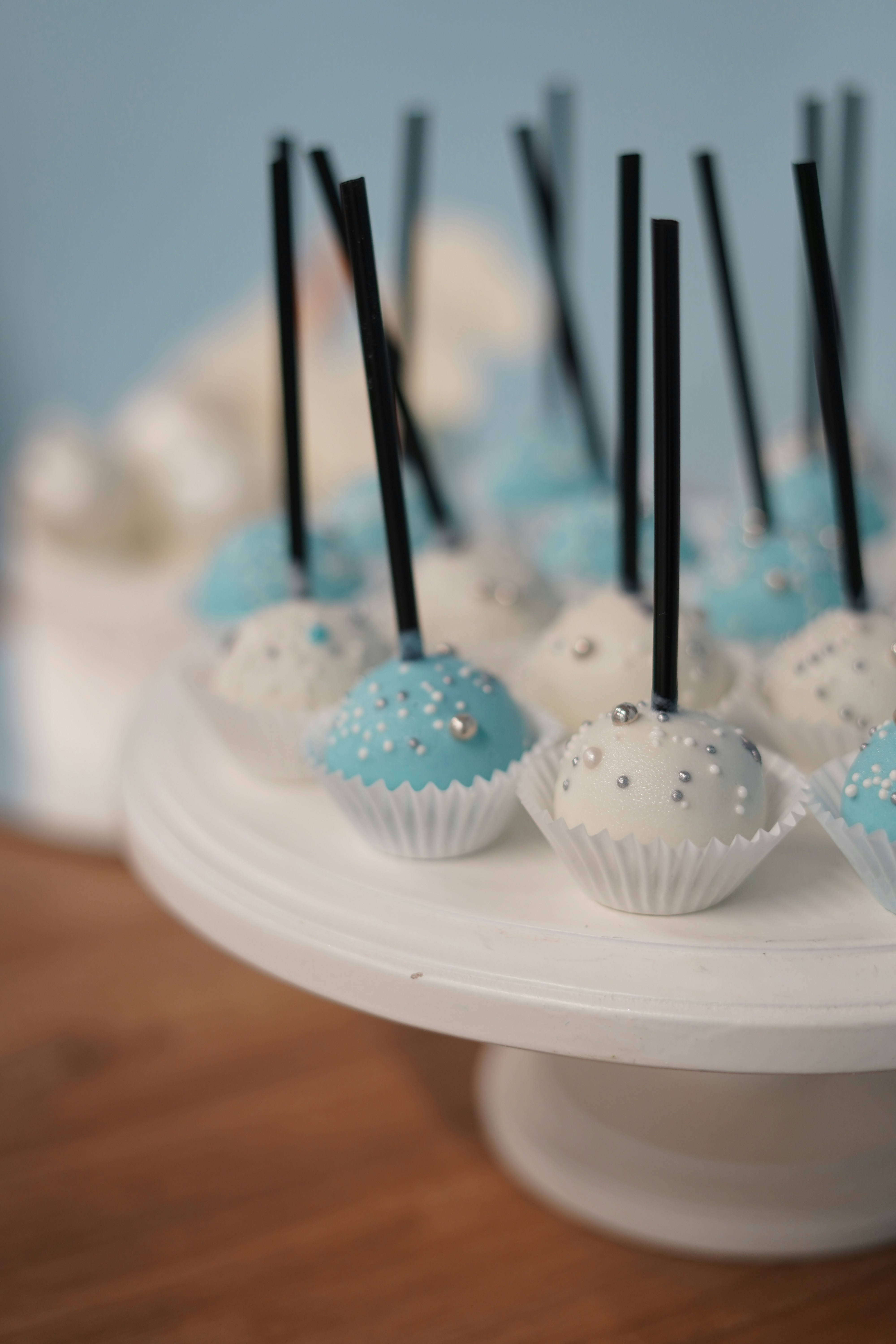 A white cake plate topped with blue and white cupcakes