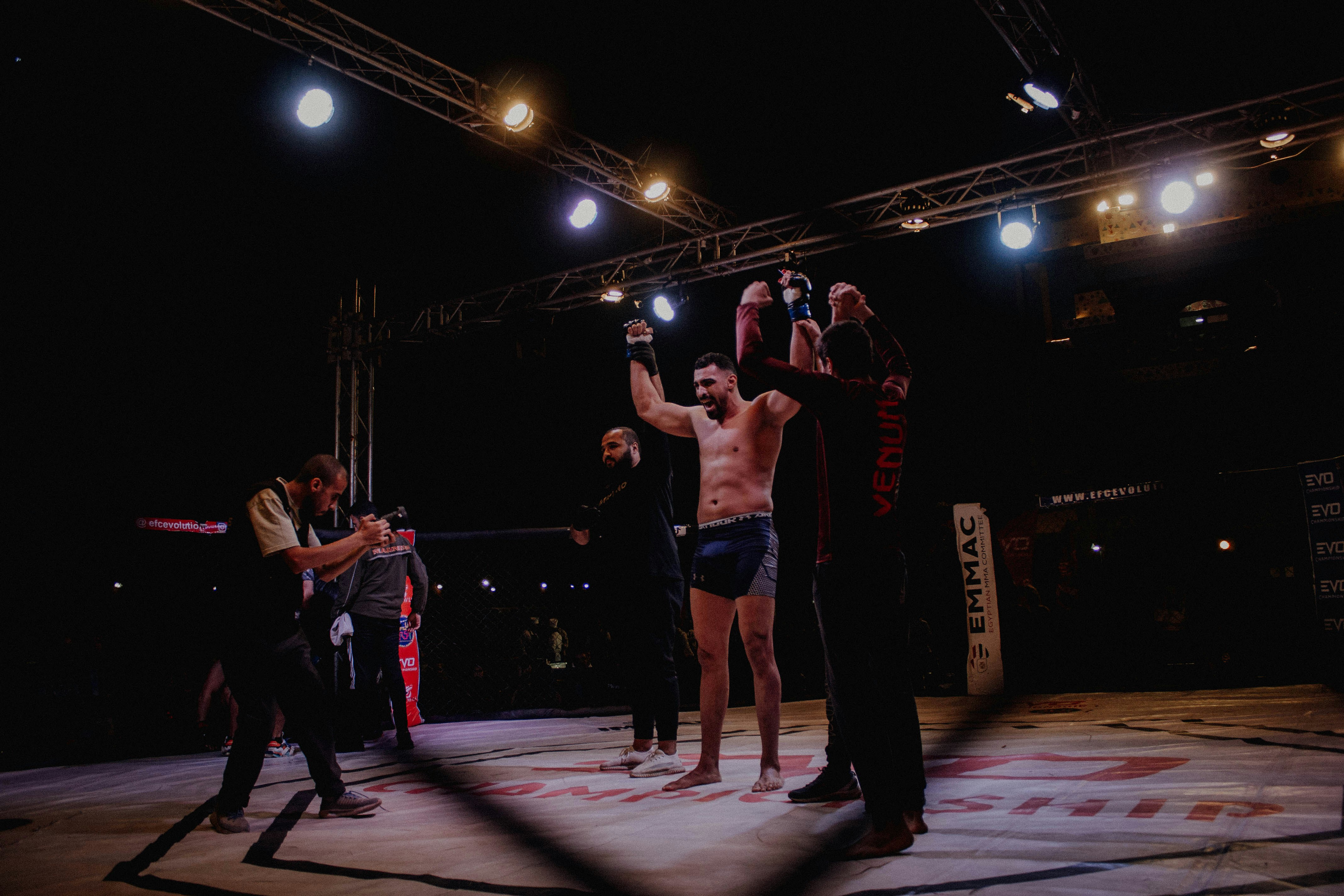 MMA fighter celebrating victory in bright arena, crowd in background