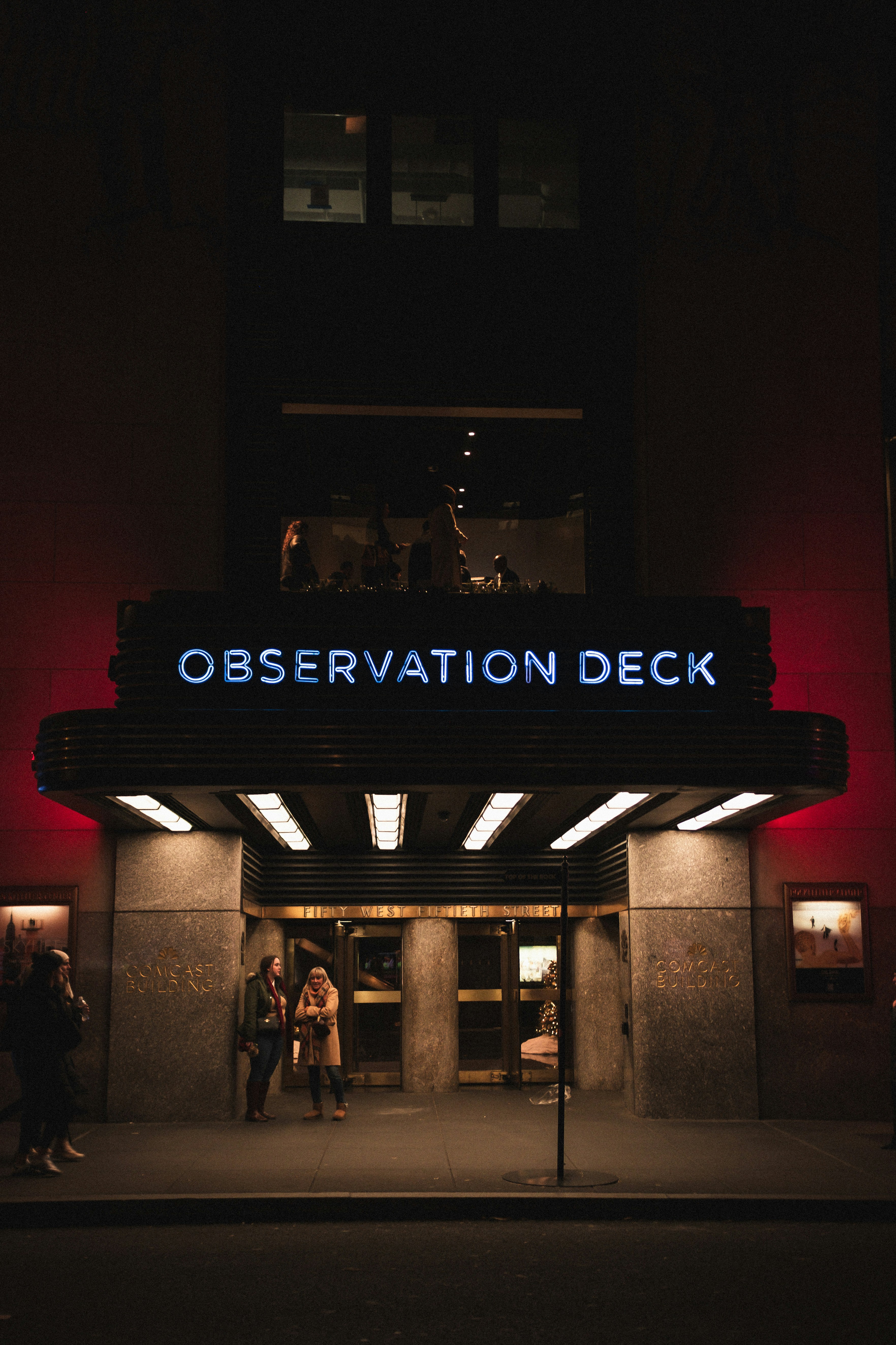 A movie theater entrance at night with people standing outside