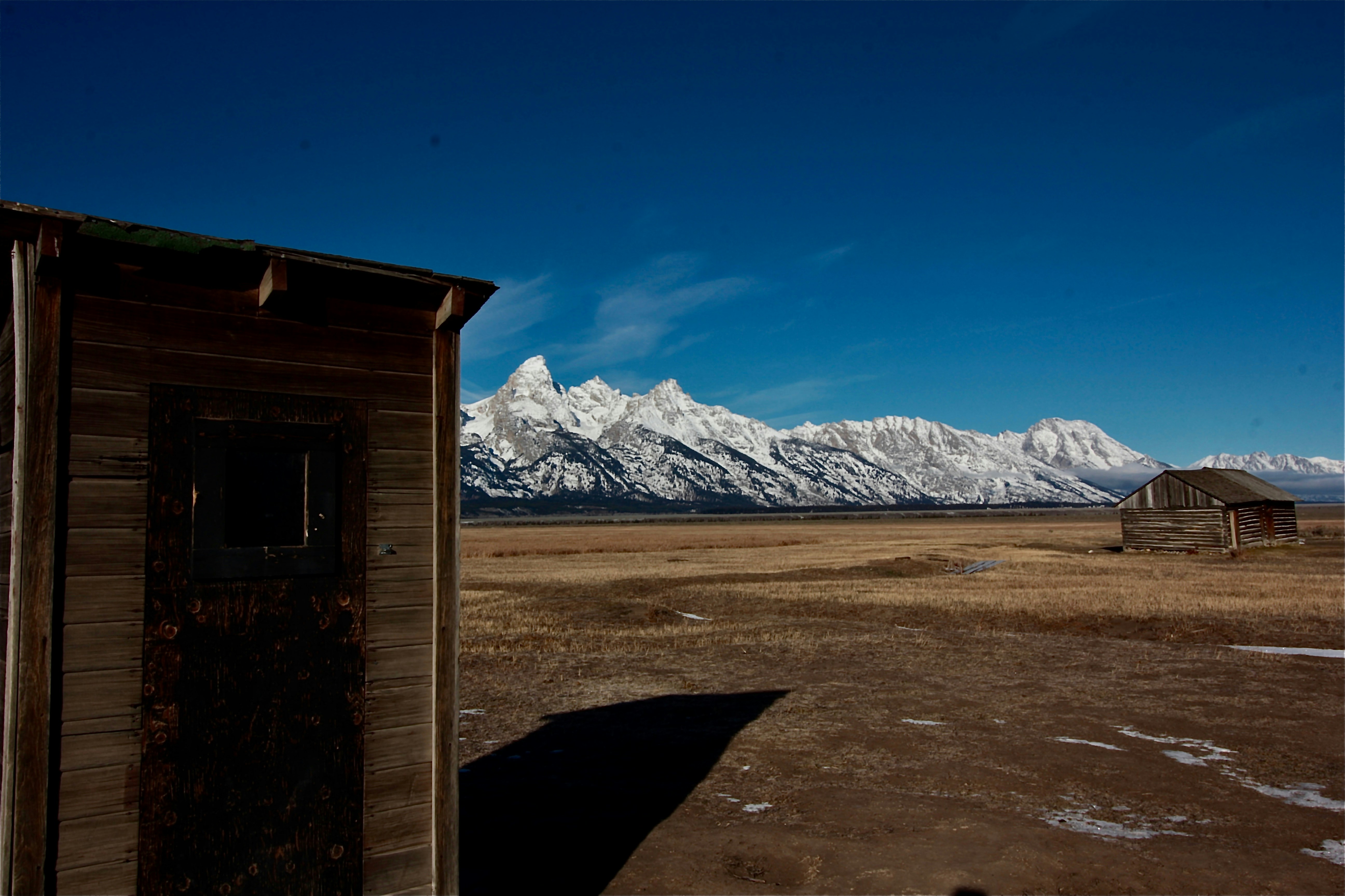 An outhouse in a field with mountains in the background