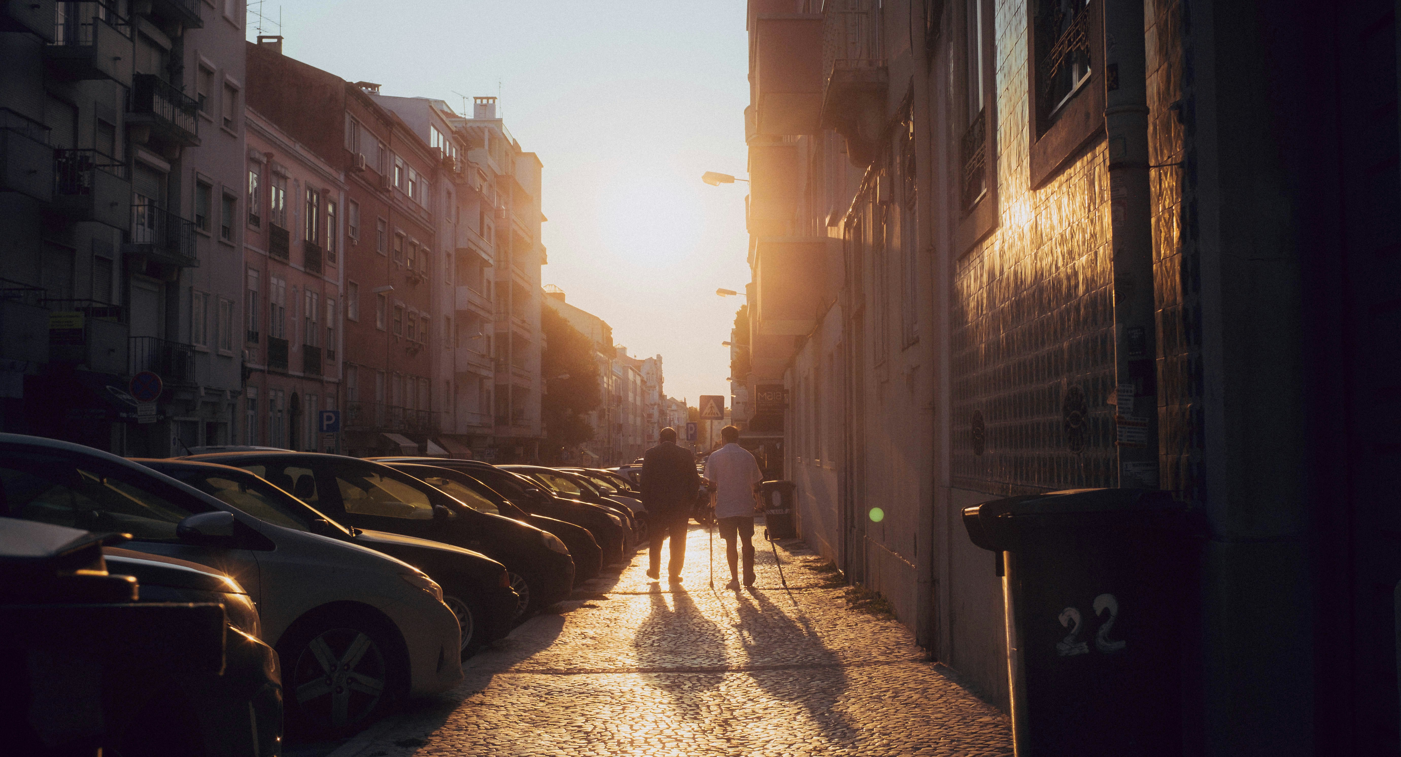 A couple of people walking down a street next to tall buildings