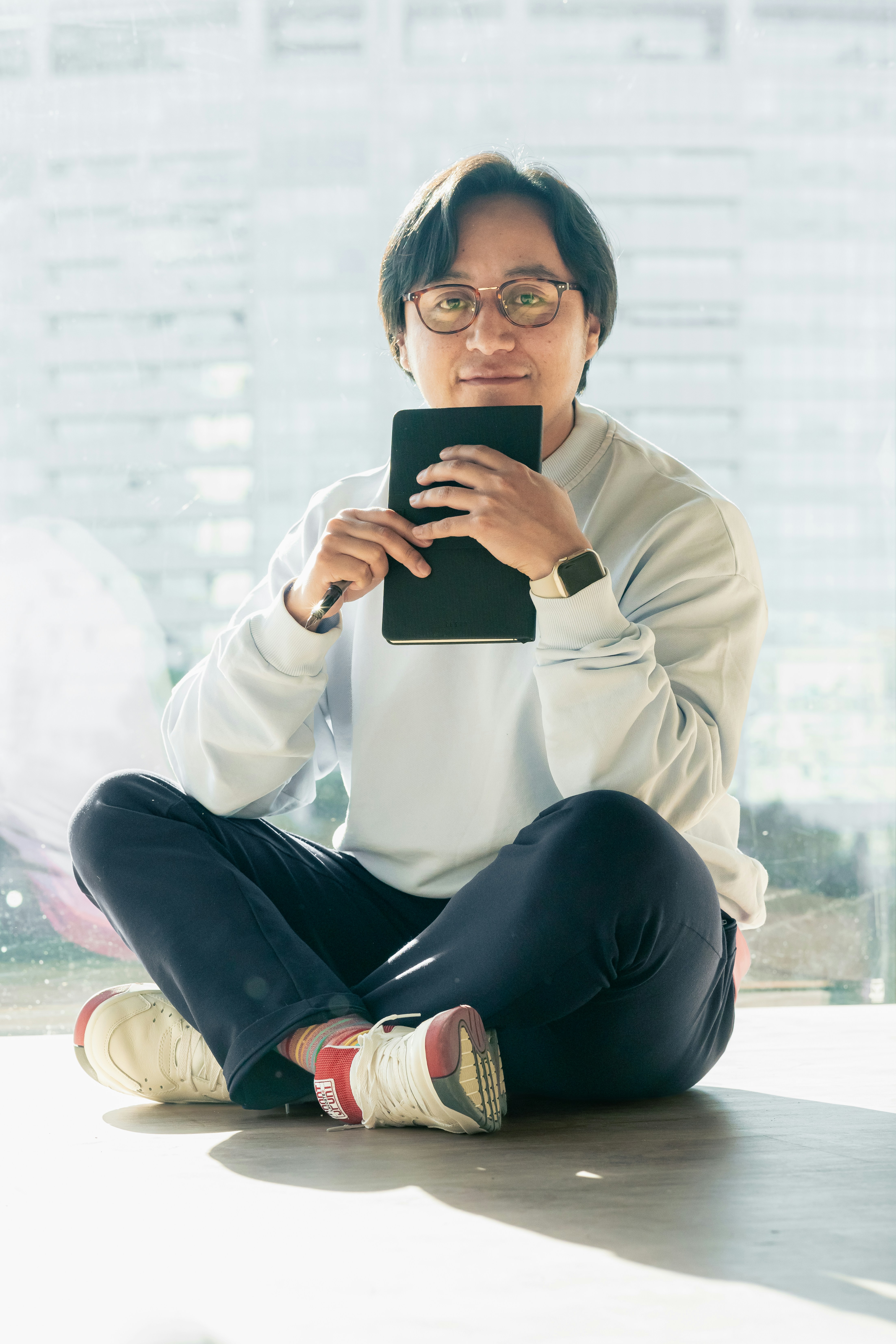 Seorang wanita duduk di lantai memegang ponsel