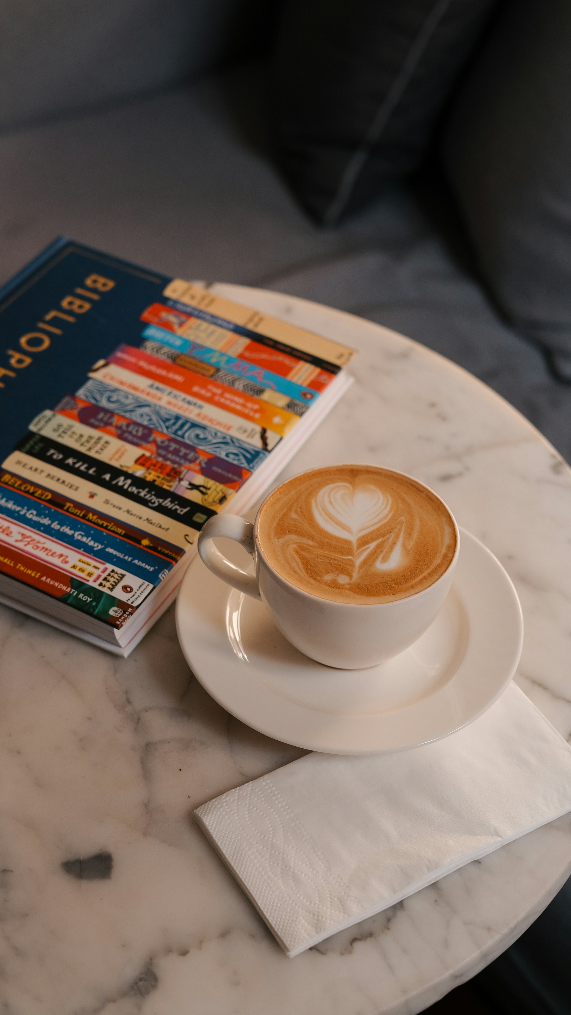 A cup of coffee and a stack of books on a marble table