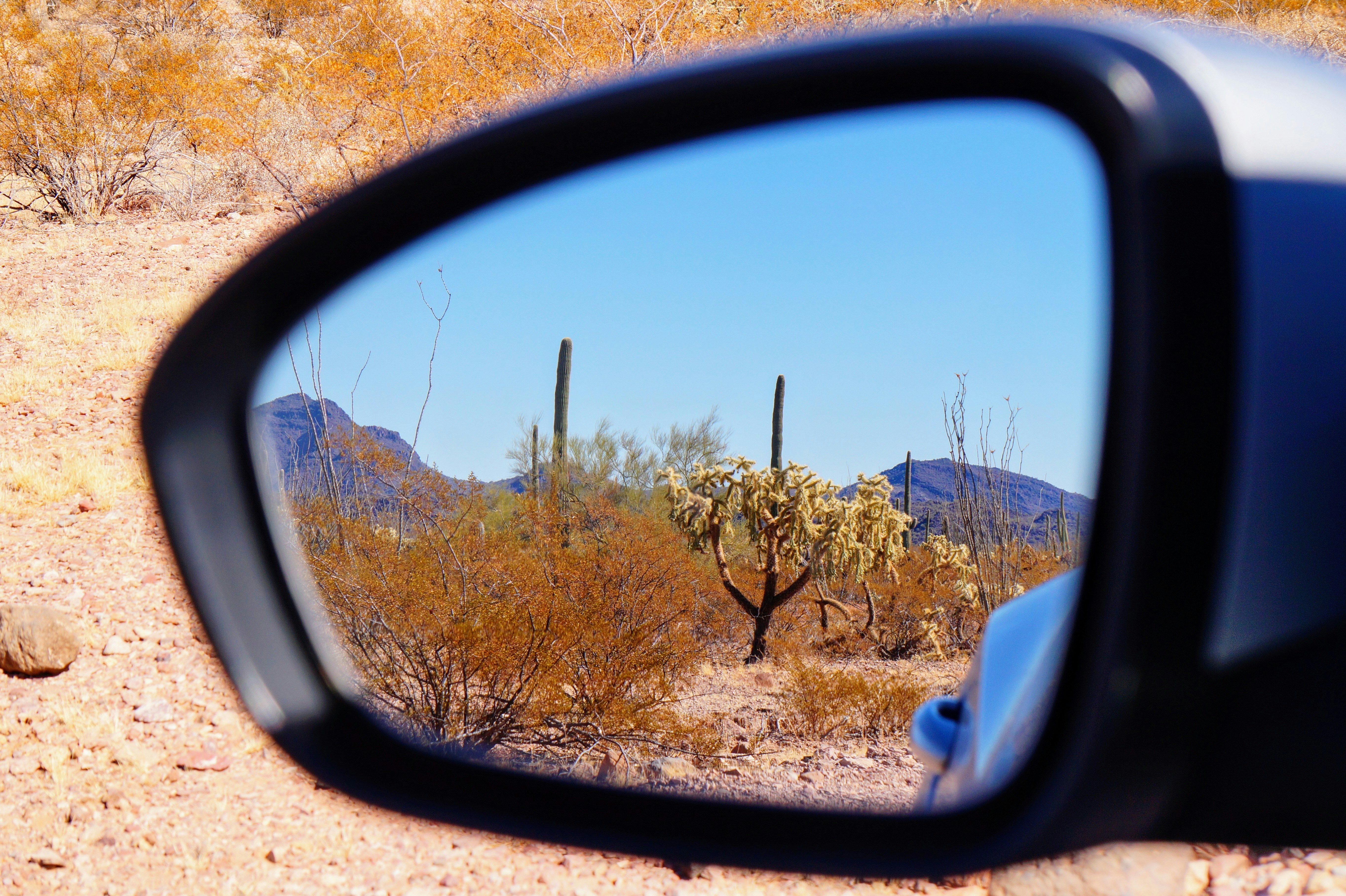 A side view mirror on a car in the desert