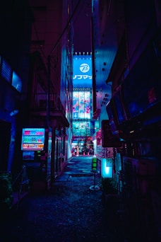 A dark alley way with neon signs on it