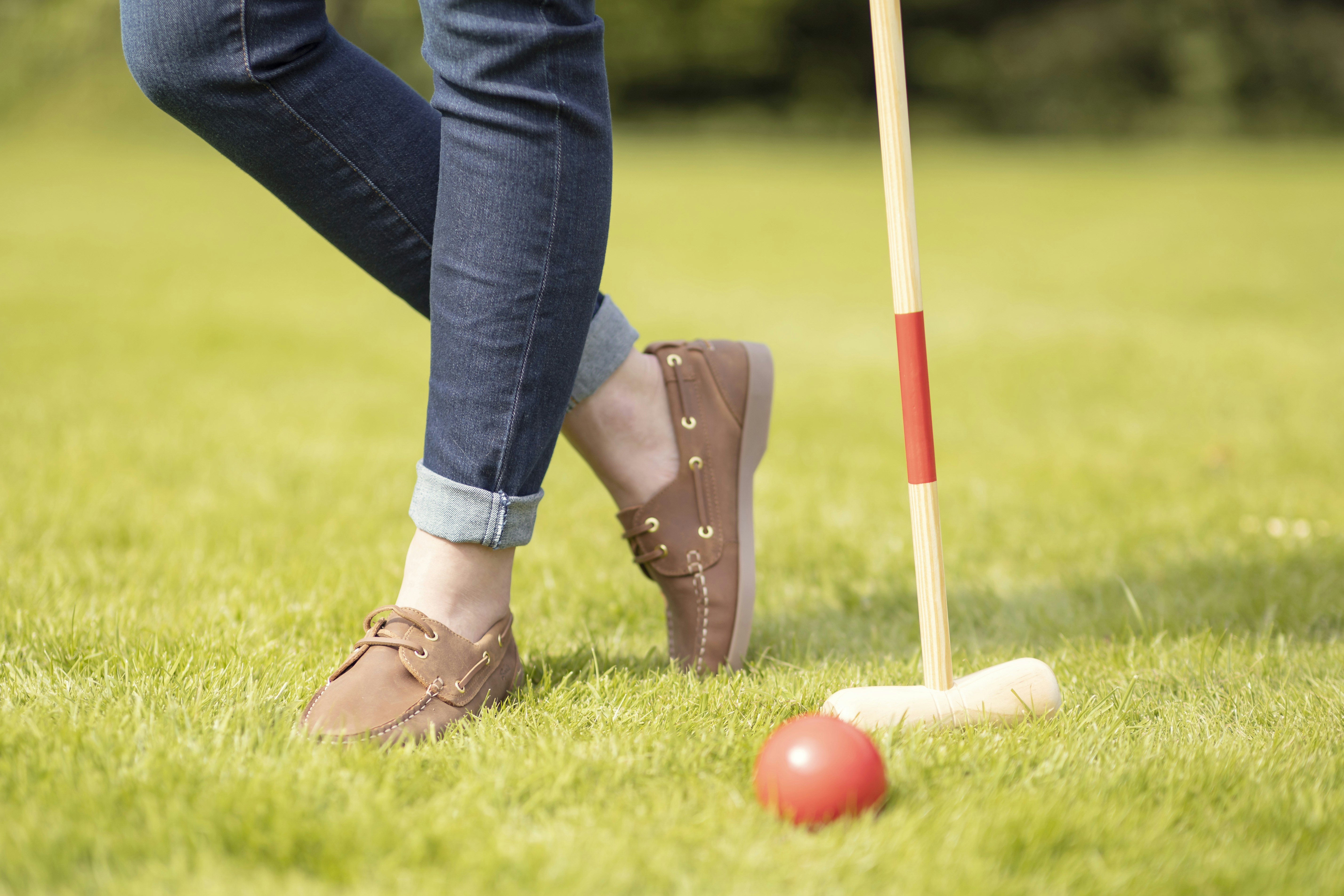 A person standing next to a red ball on a green field