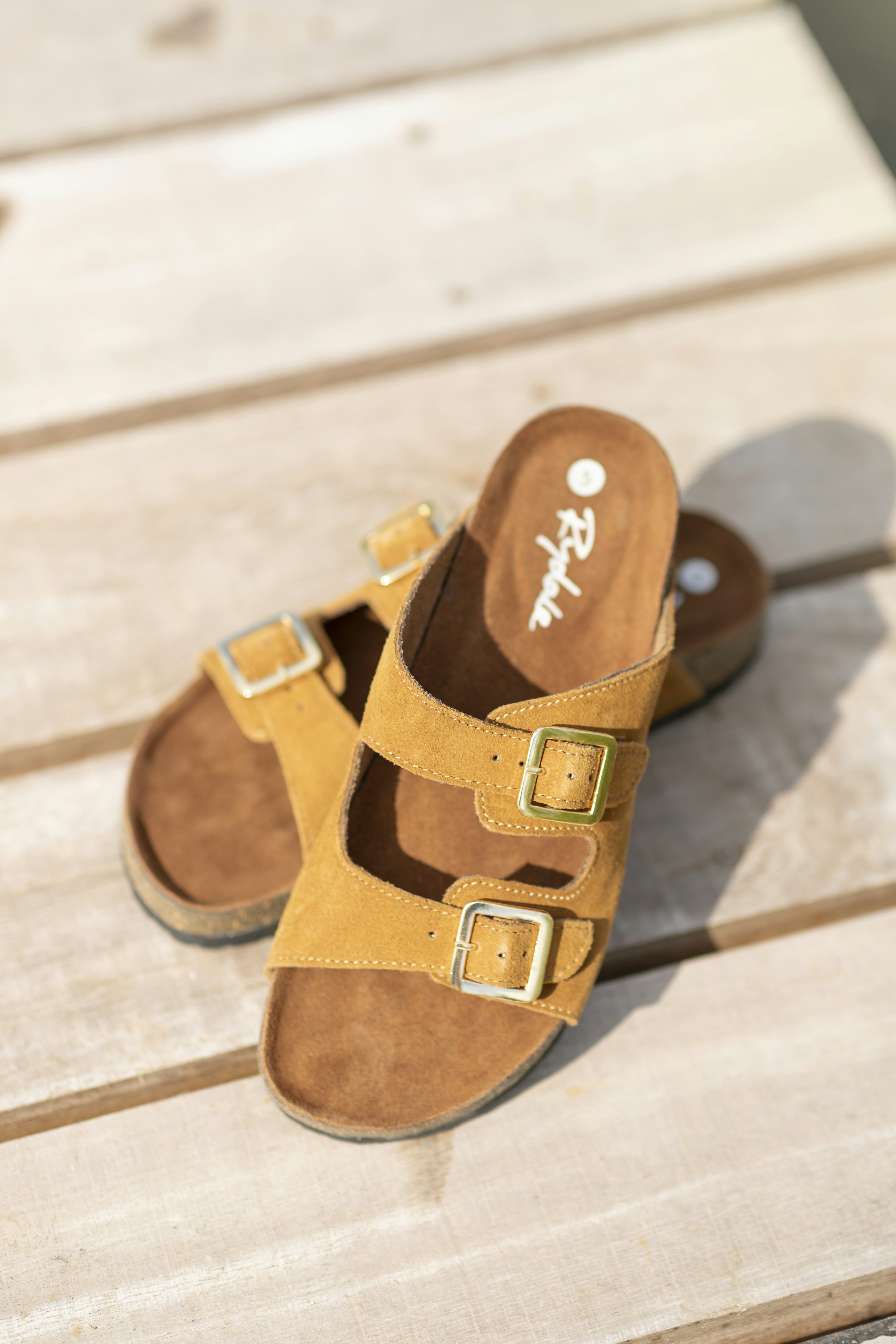 A pair of brown sandals sitting on top of a wooden floor