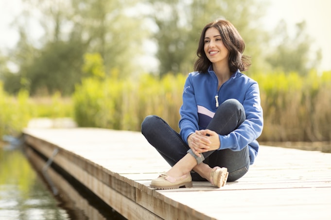 A woman is sitting on a dock by the water