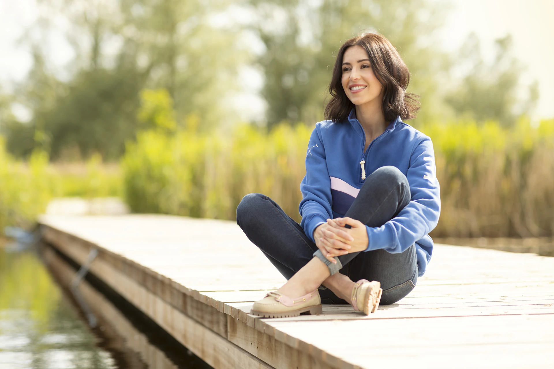 A woman is sitting on a dock by the water