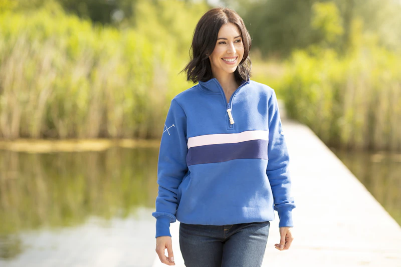 femme en pull bleu marchant près de l'eau
