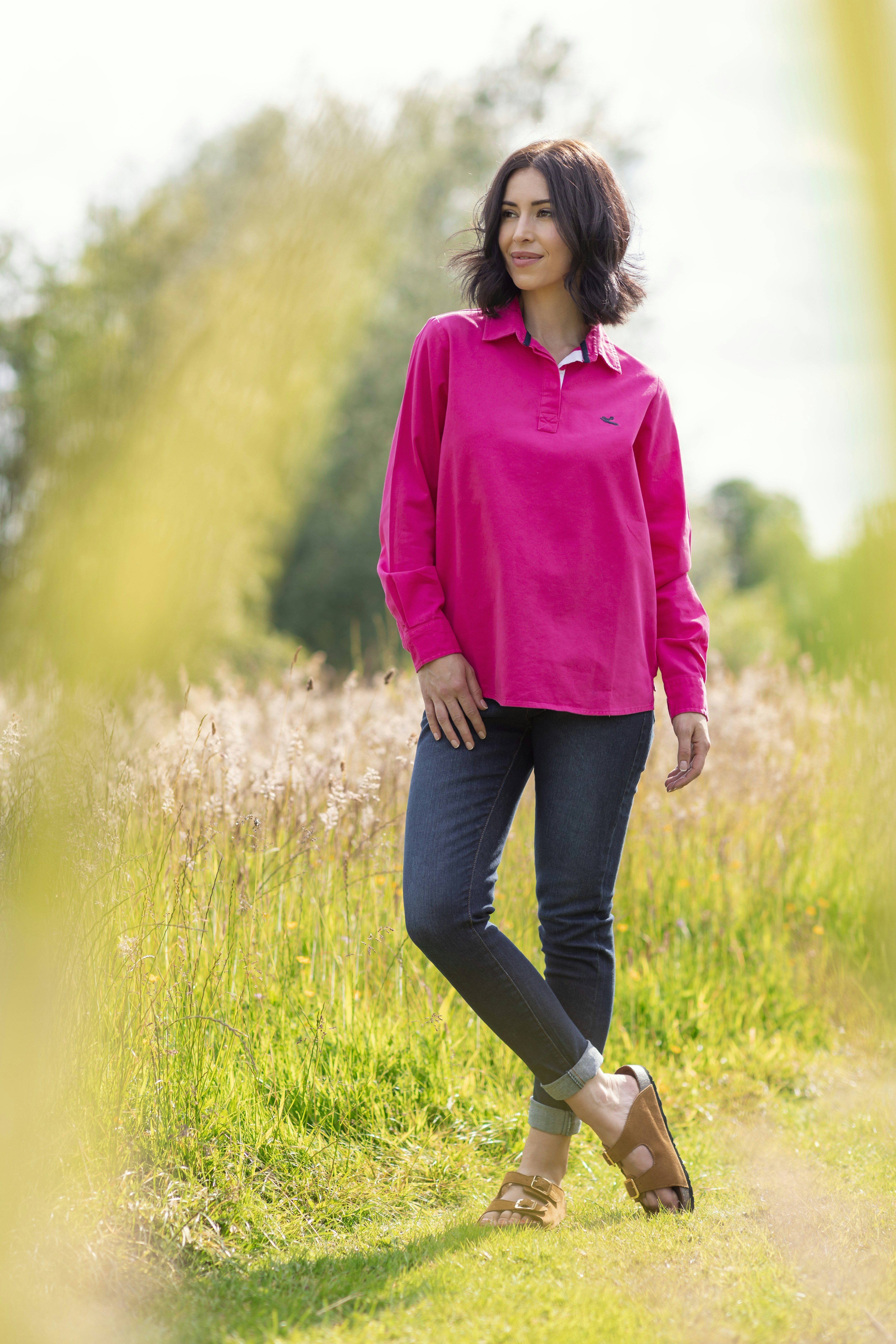 A woman in a pink shirt is standing in a field
