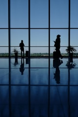 A couple of people that are standing in front of a window