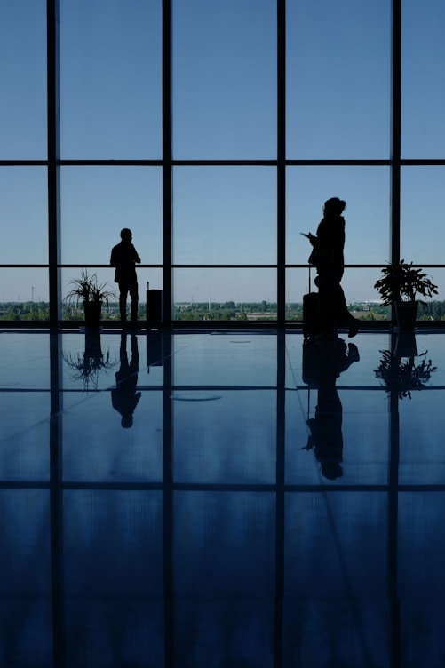 A couple of people that are standing in front of a window
