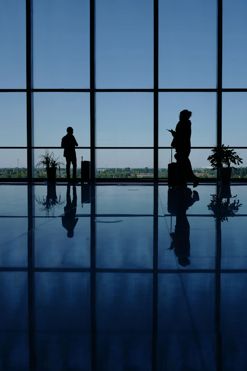 A couple of people that are standing in front of a window