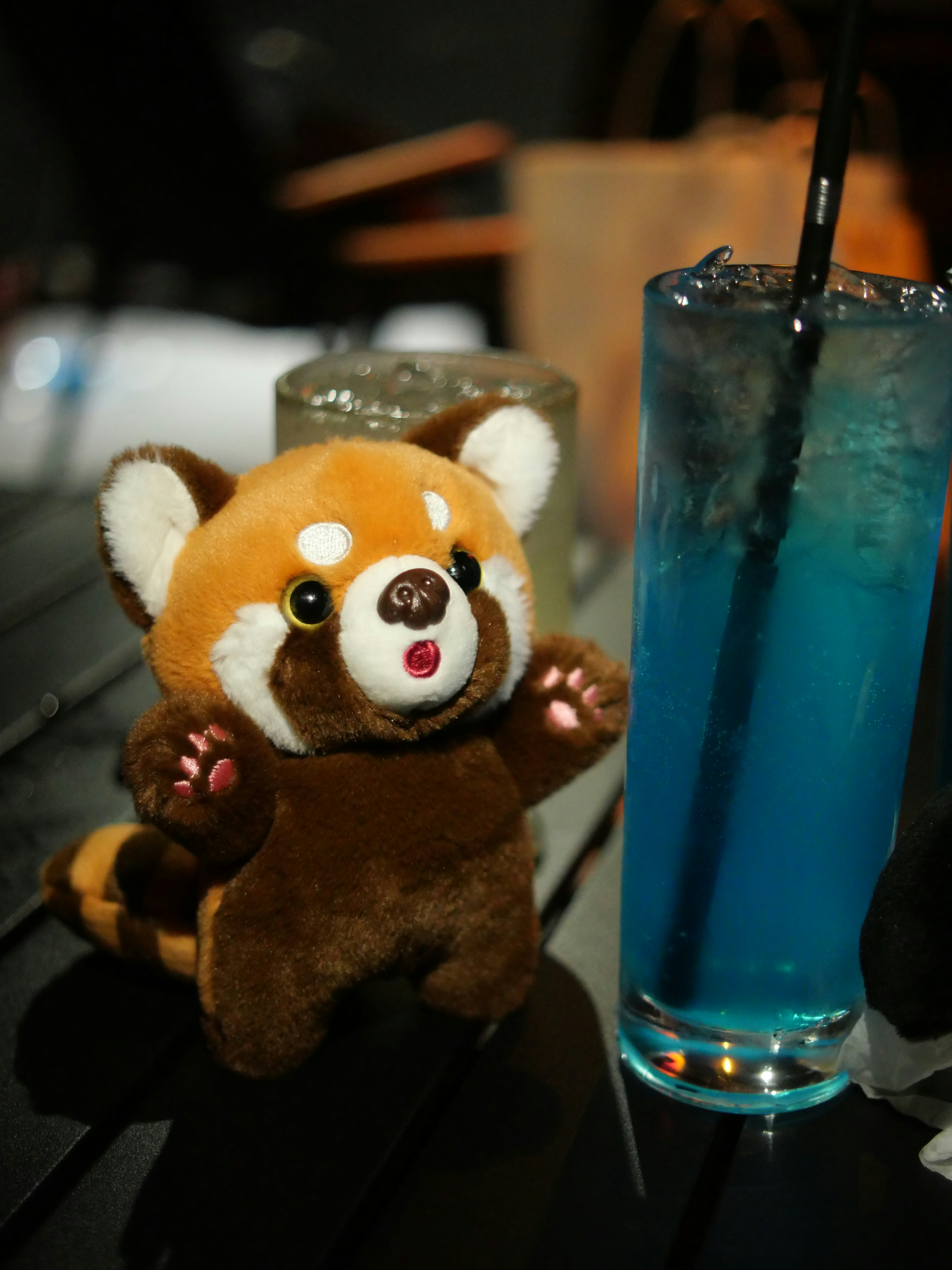 A stuffed animal next to a drink on a table