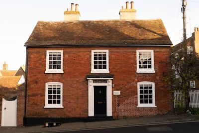 A red brick house with white windows and a black door