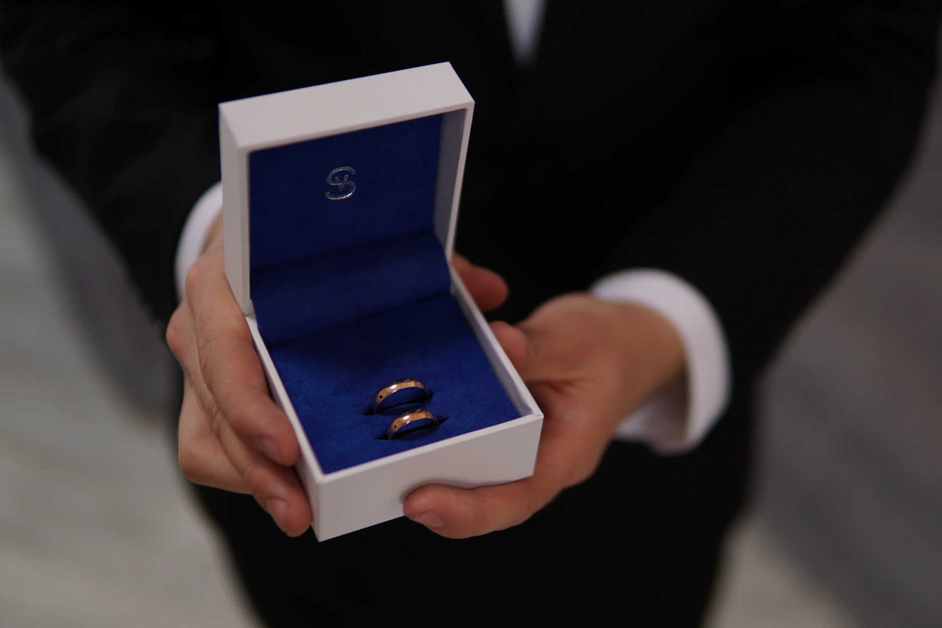 A man in a suit holding a ring in a box