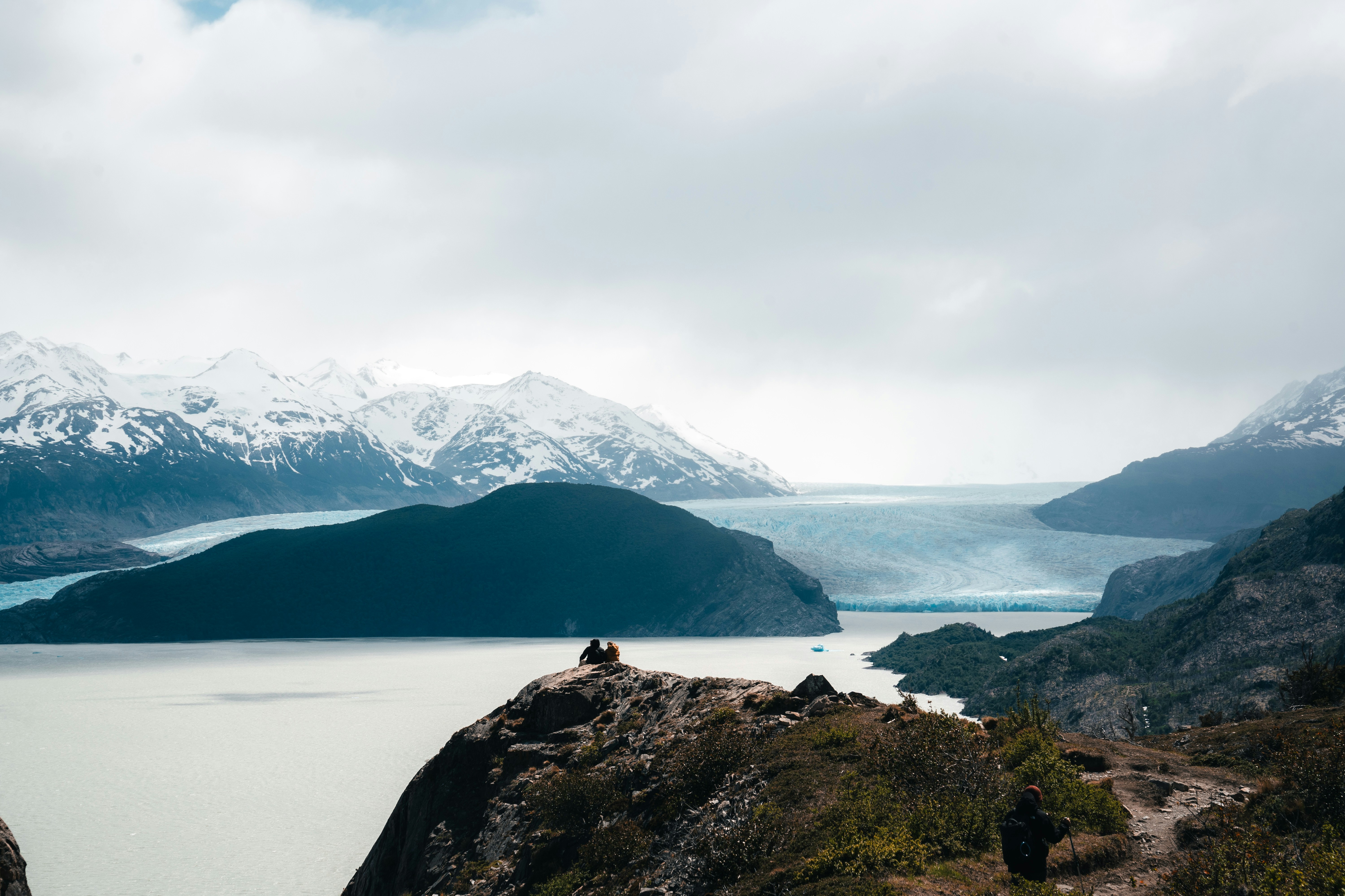 A person sitting on a rock overlooking a lake and mountains