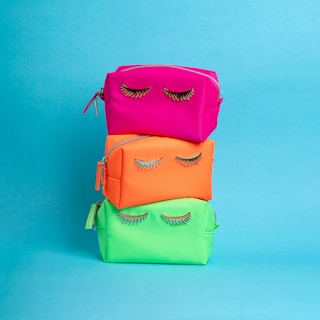 A stack of three colorful bags with eyelashes on them