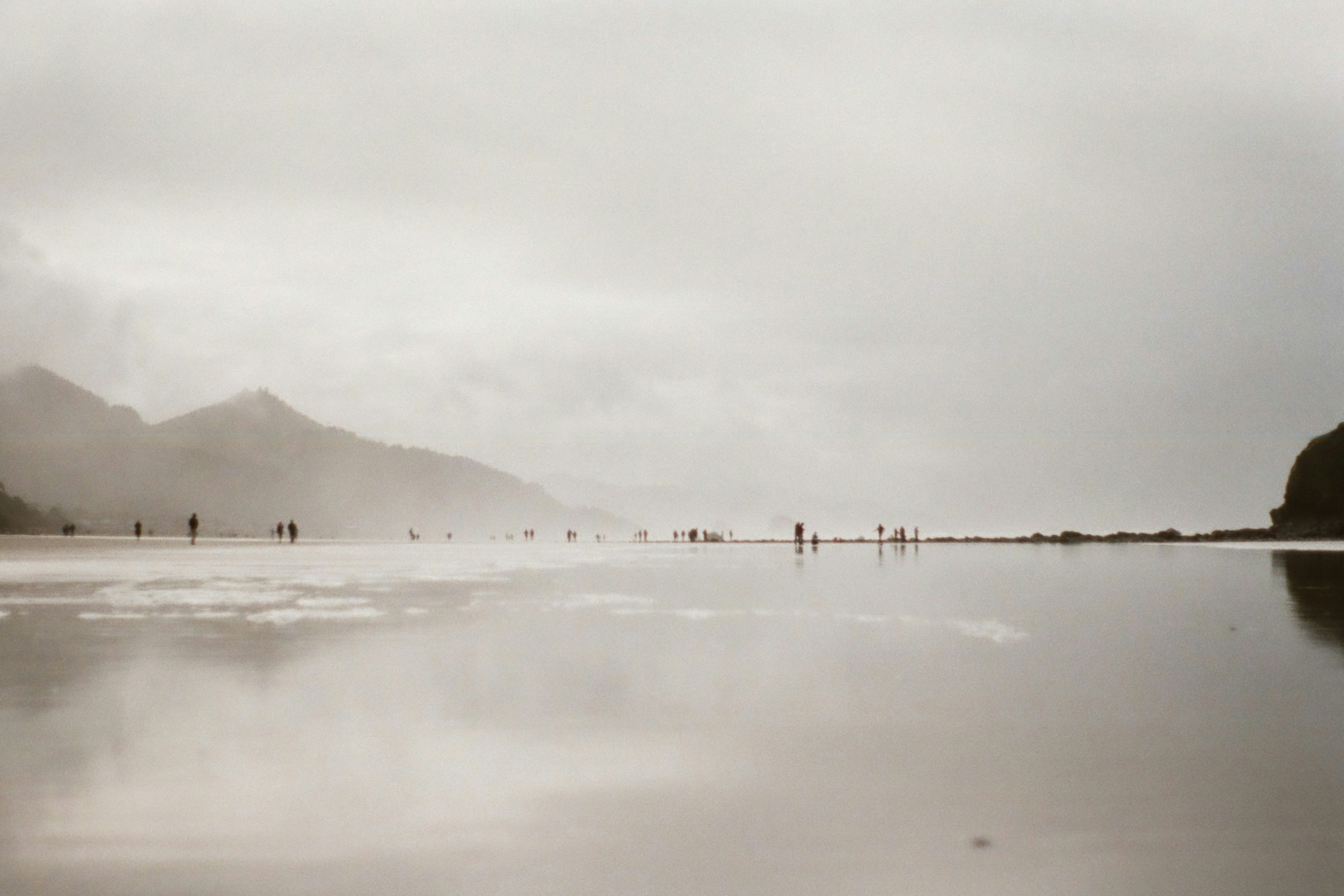 A black and white photo of people walking on a beach