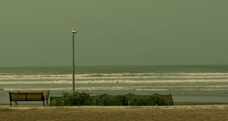 A bench sitting on top of a sandy beach next to the ocean