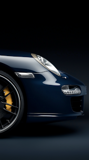 A blue sports car is shown in a dark room