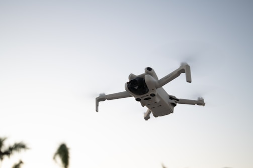 A white camera flying through the air with trees in the background