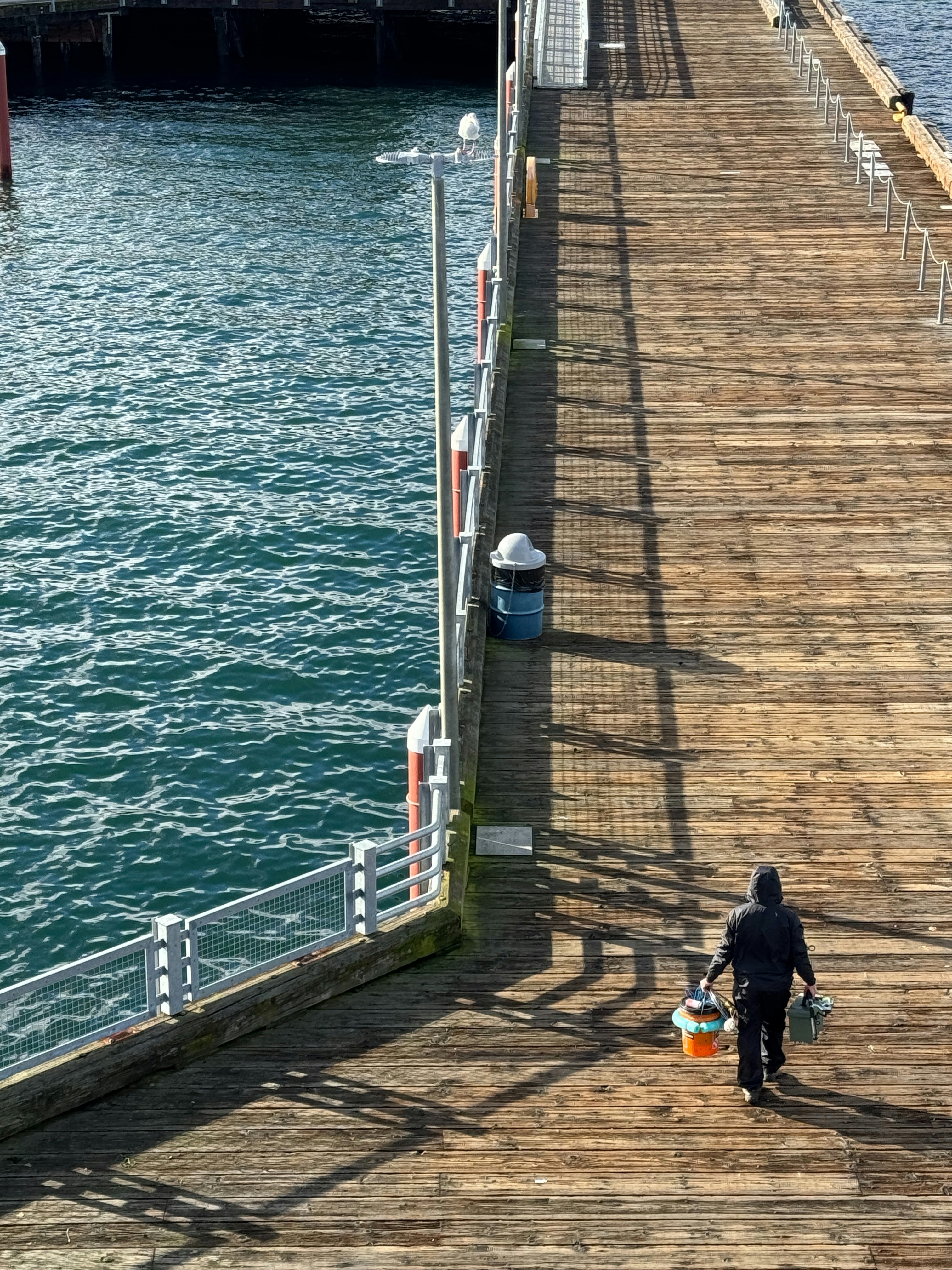 A man walking down a pier next to a body of water