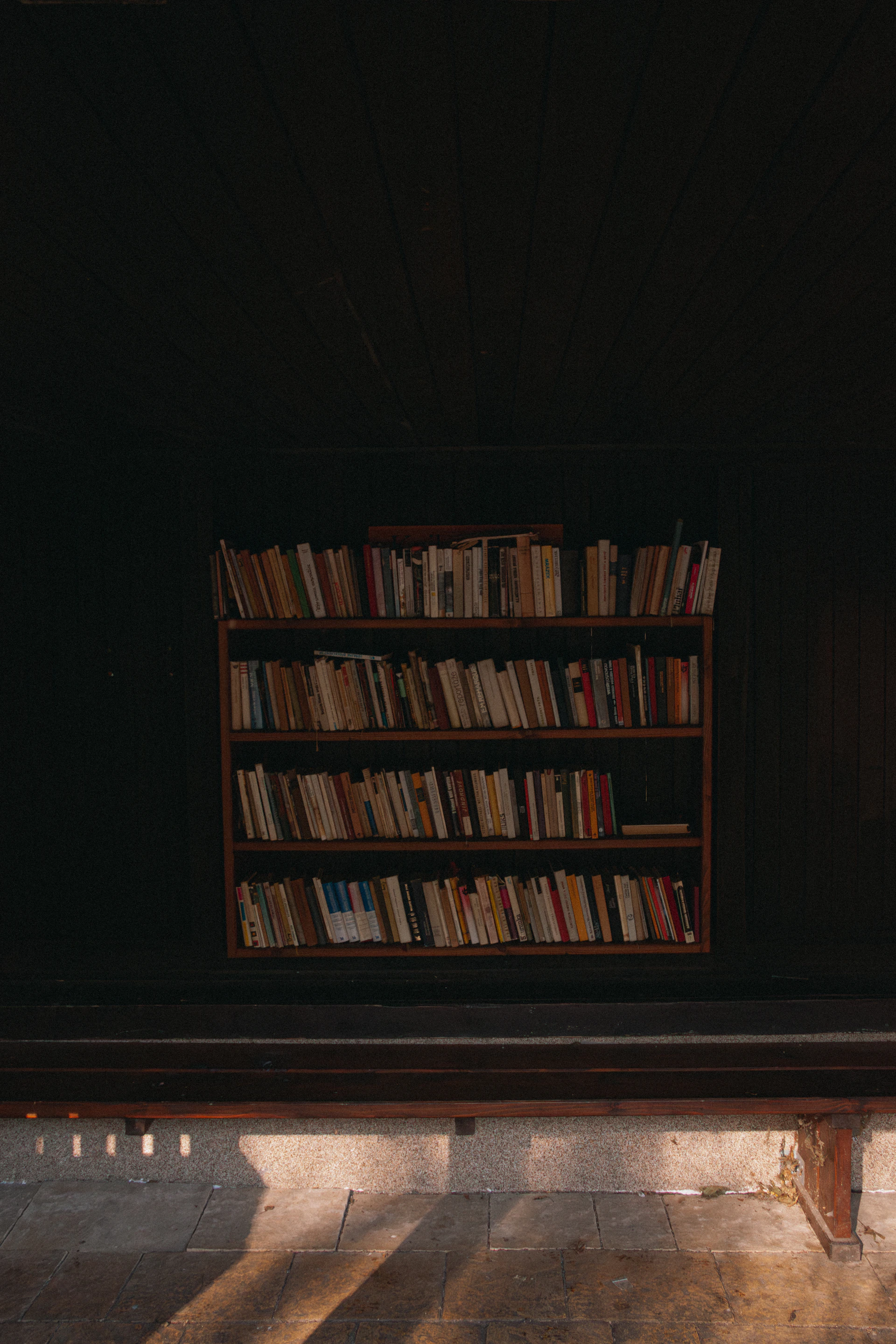 A wooden bench sitting in front of a book shelf