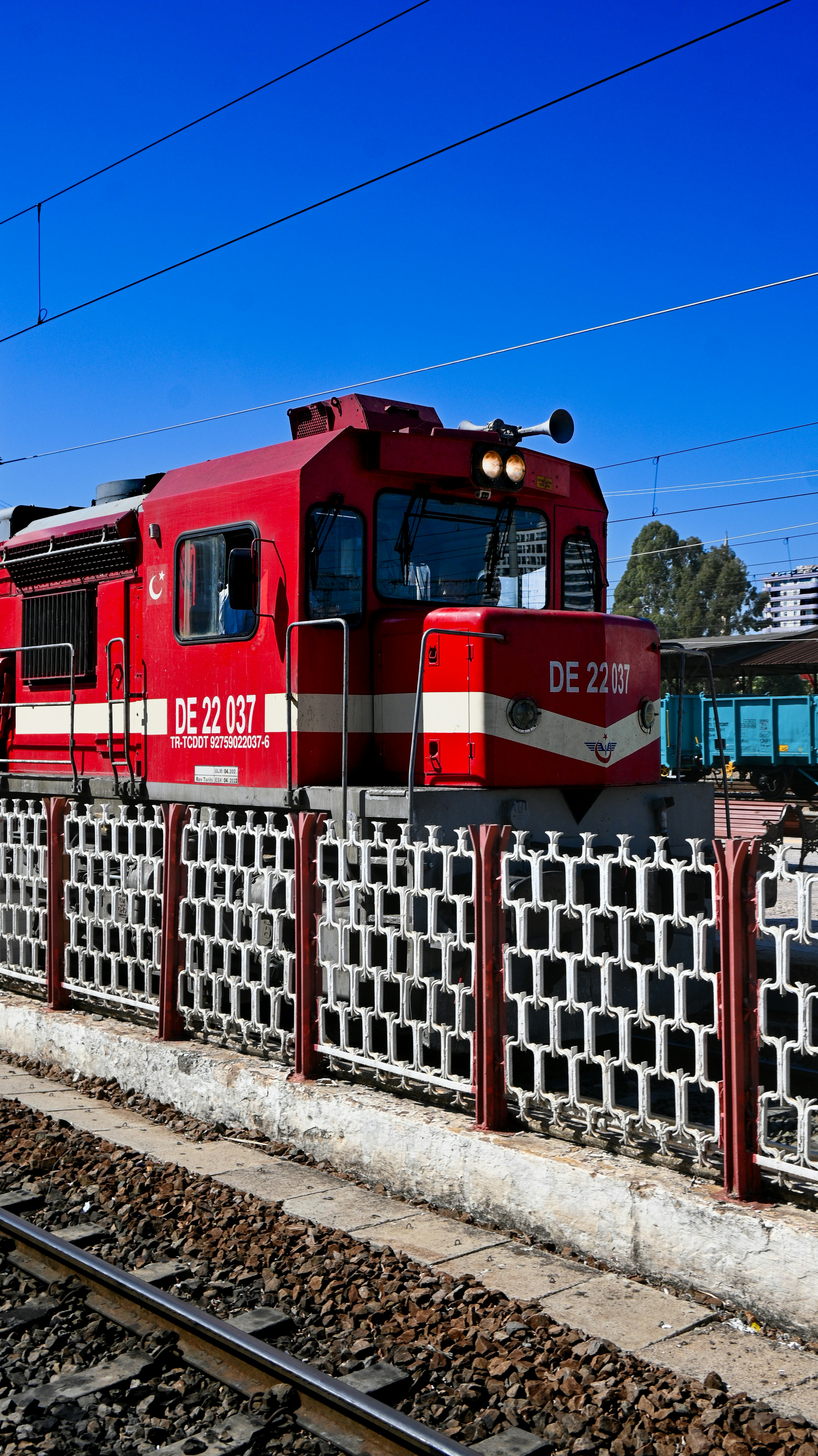 A red train traveling down train tracks next to a fence