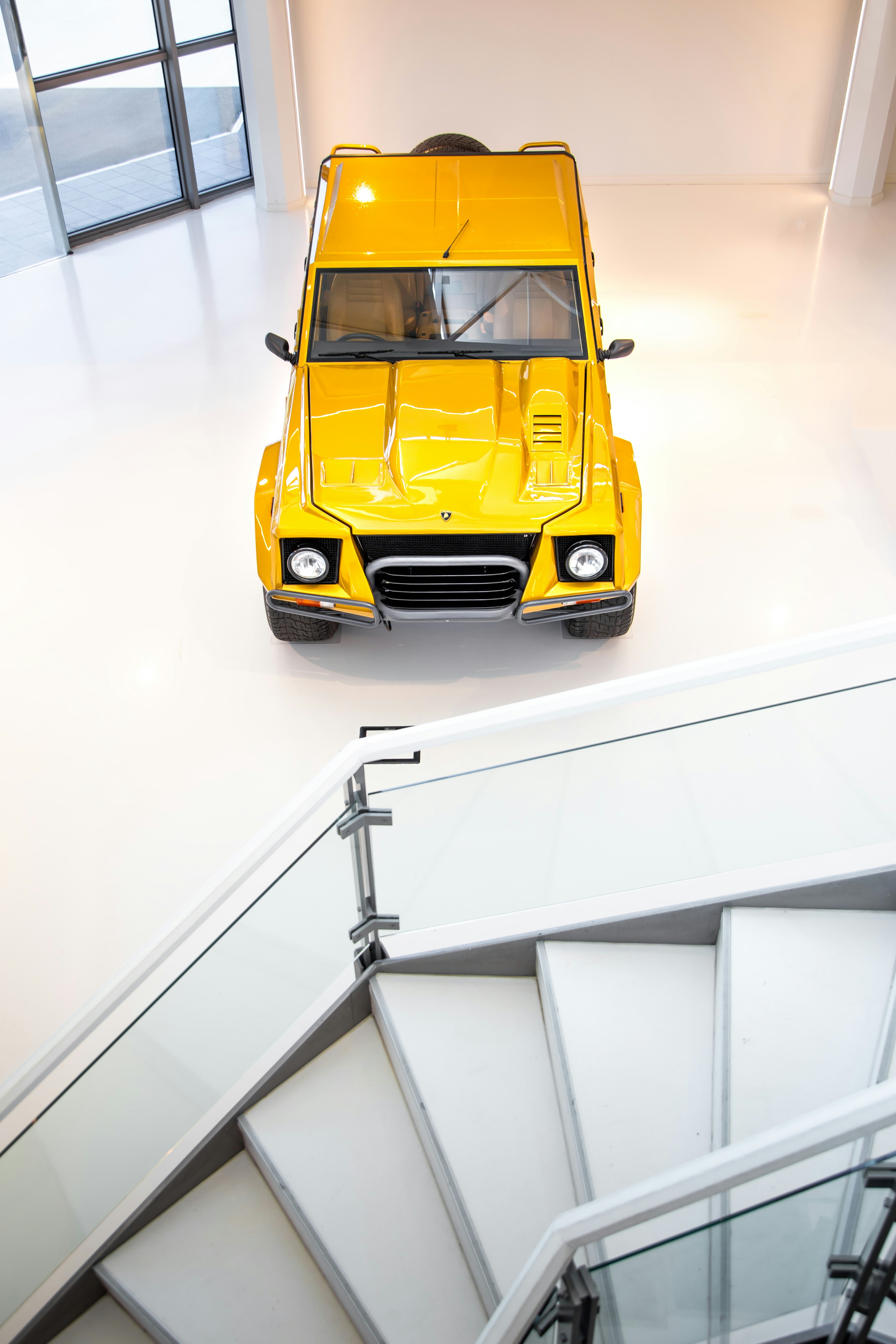 SUV d'epoca gialla parcheggiata su un pavimento bianco in uno showroom.