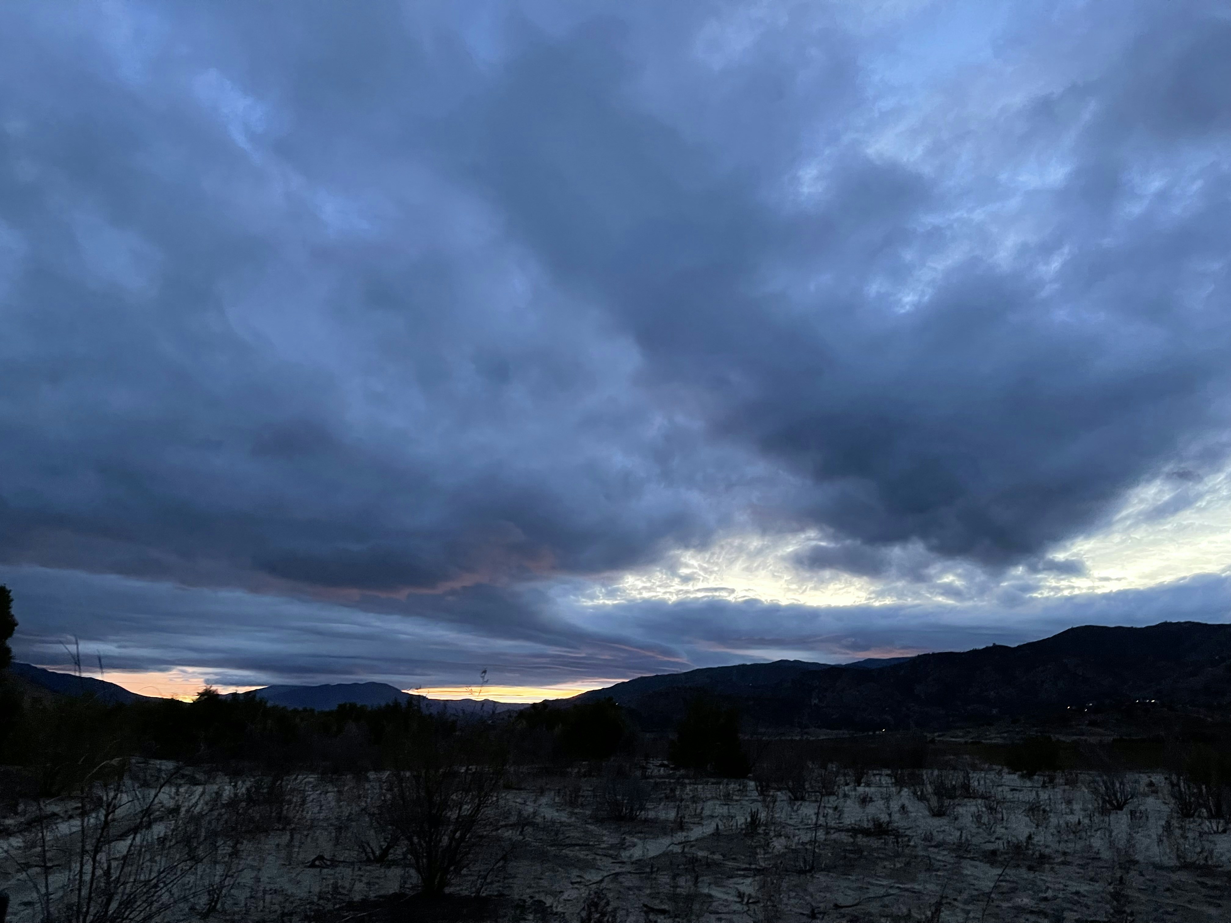 Dramatic mountain landscape at dusk with deep navy sky and silhouetted peaks against fading light, moody atmospheric editorial mood