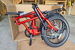 A red bicycle sitting in a cardboard box