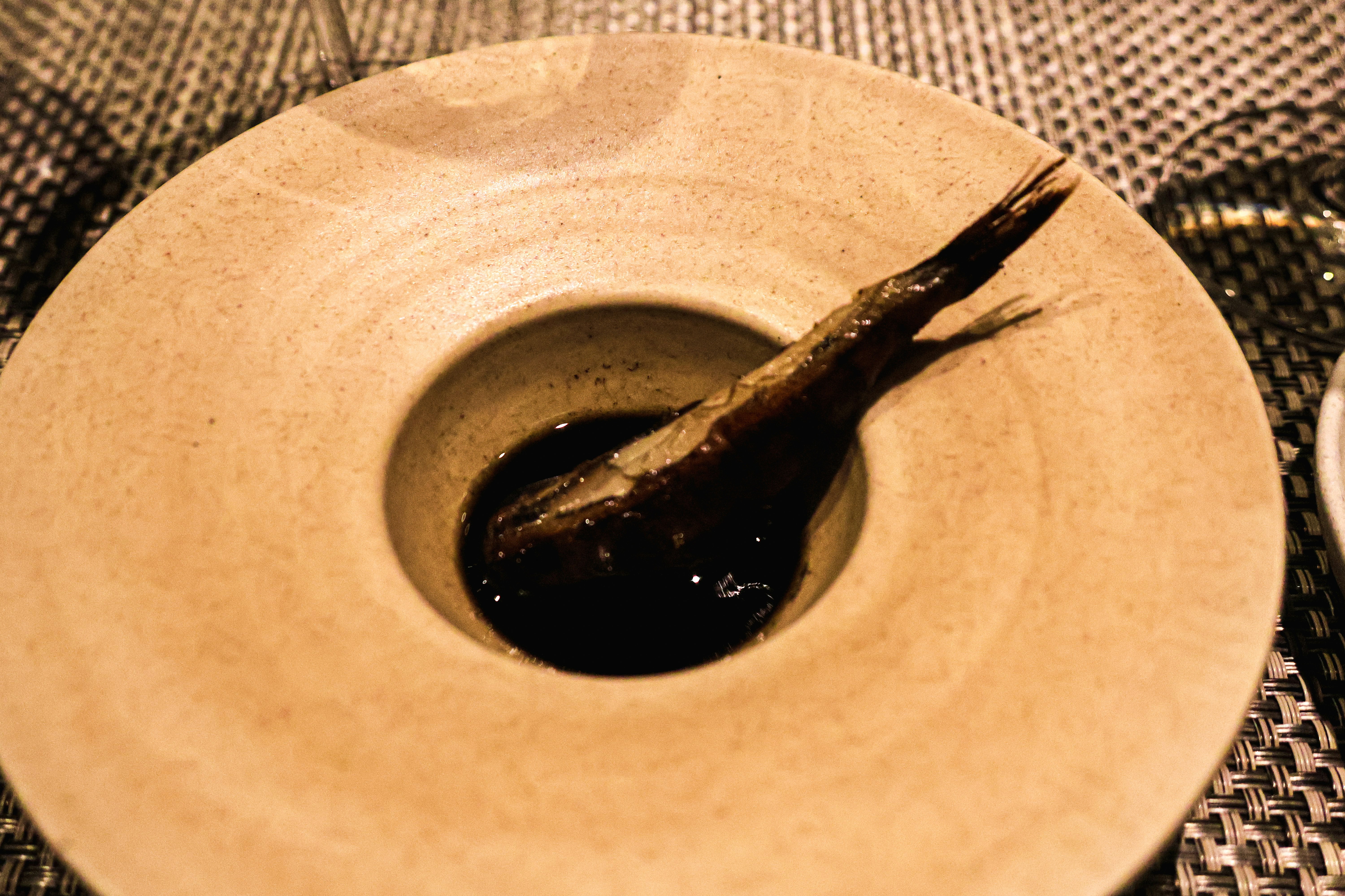 A white plate topped with a small bowl filled with liquid