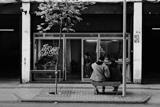 A black and white photo of a person sitting on a bench