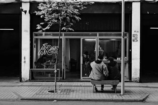 A black and white photo of a person sitting on a bench