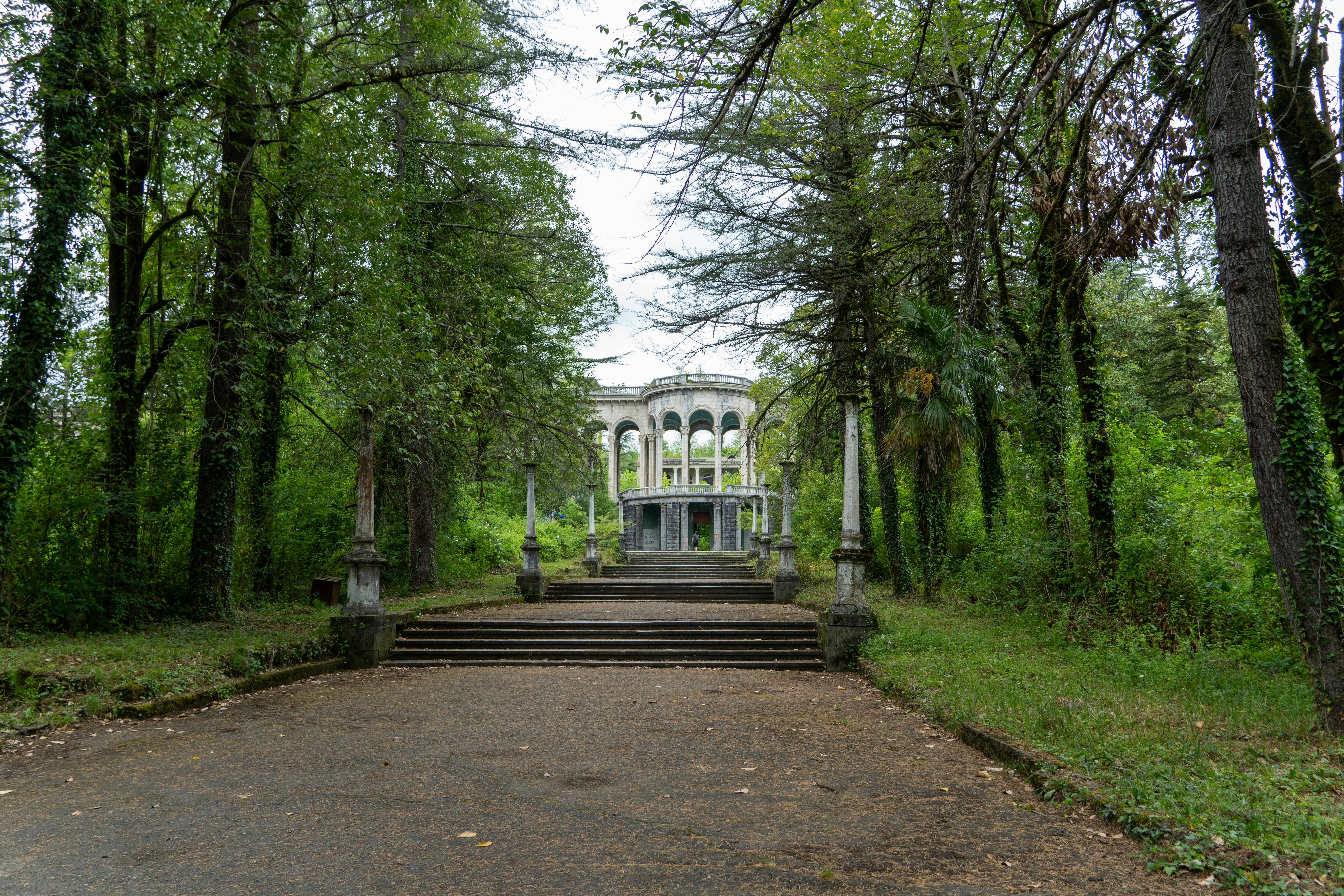 A park with a lot of trees and a building in the background