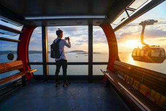 A man taking a picture of the sunset through a window