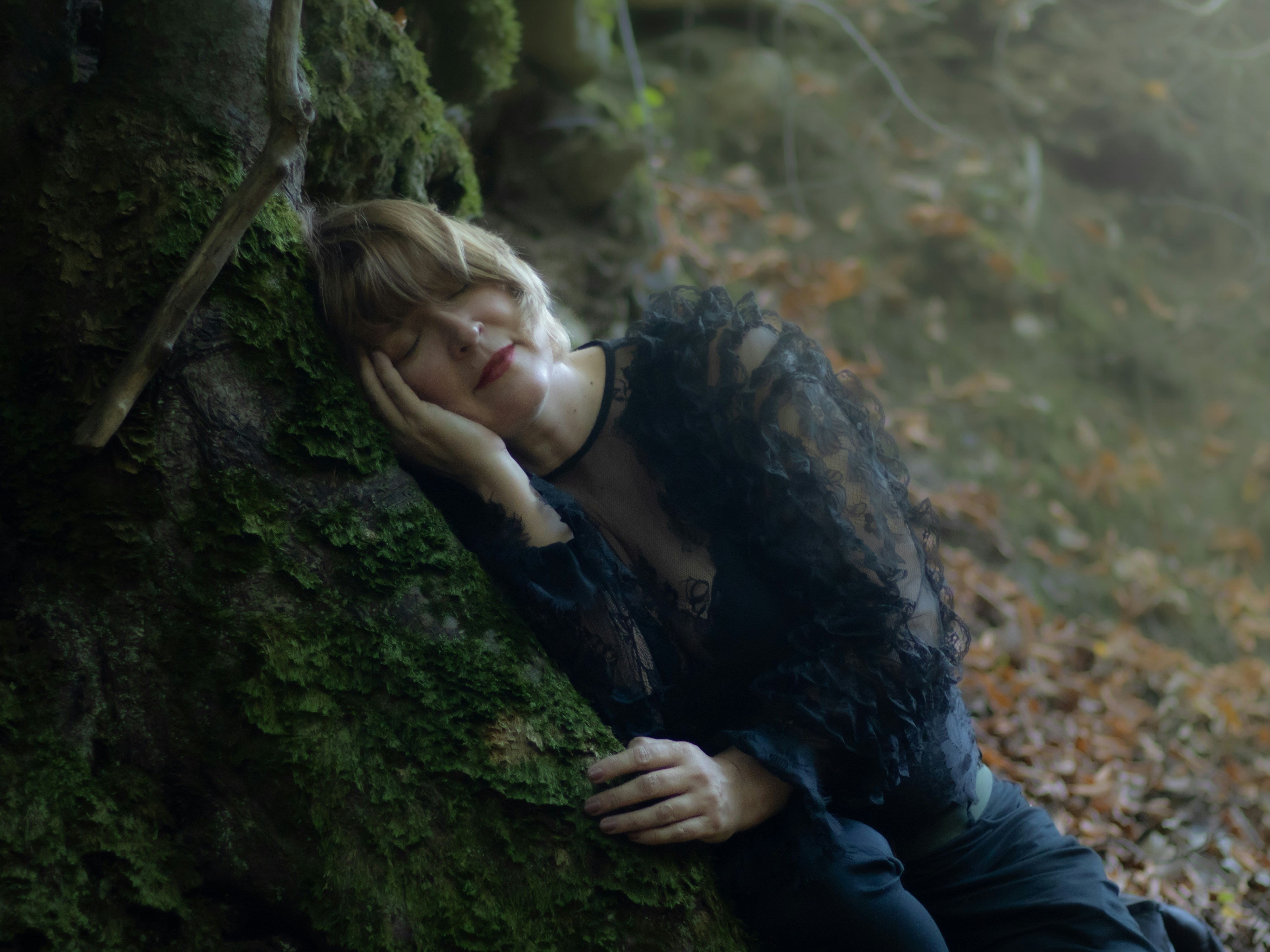 Uma mulher encostada em uma árvore na floresta