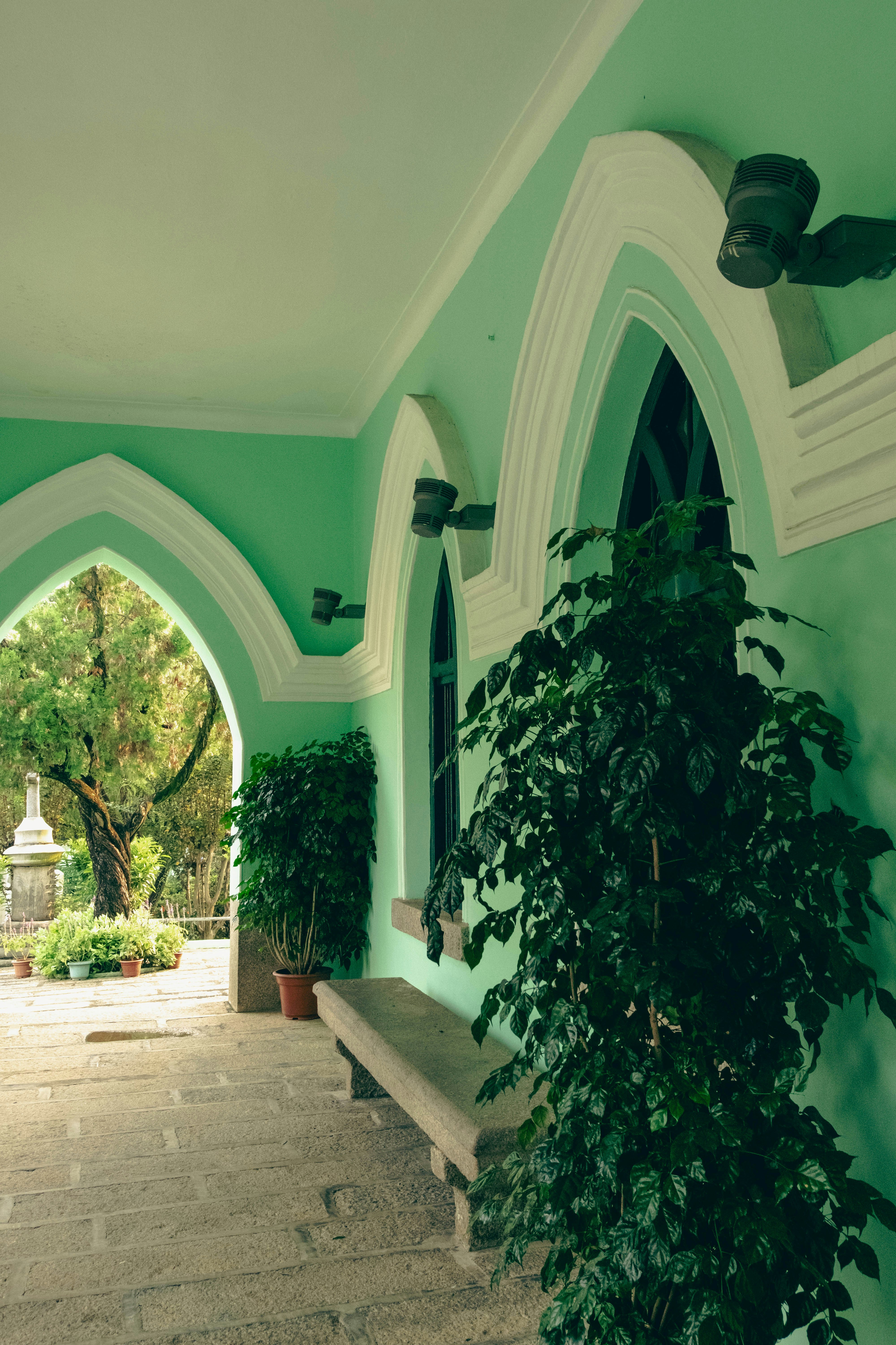 A green and white building with a bench and a potted plant
