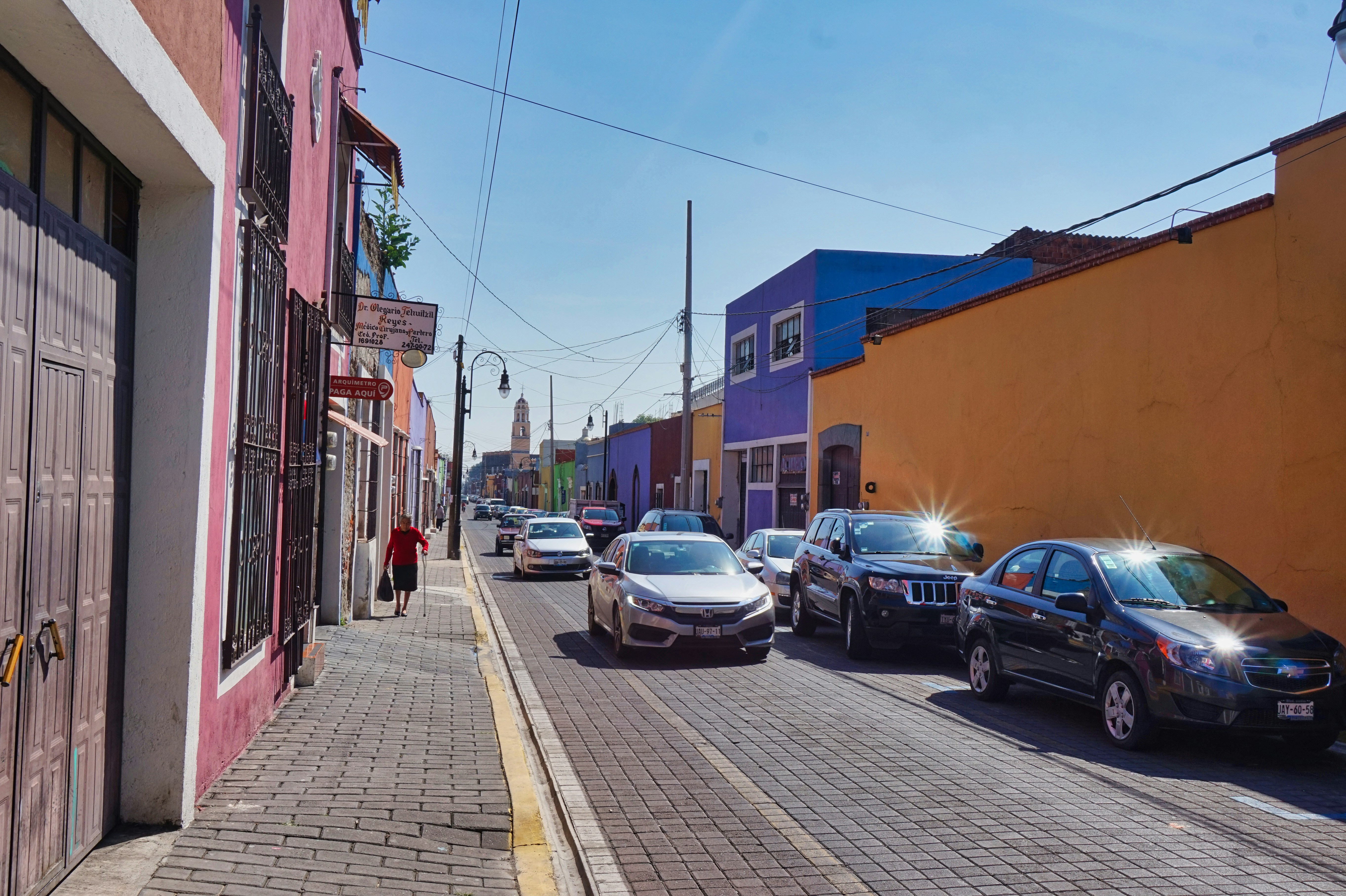 Colorful street in Mexico with parked cars and colonial buildings