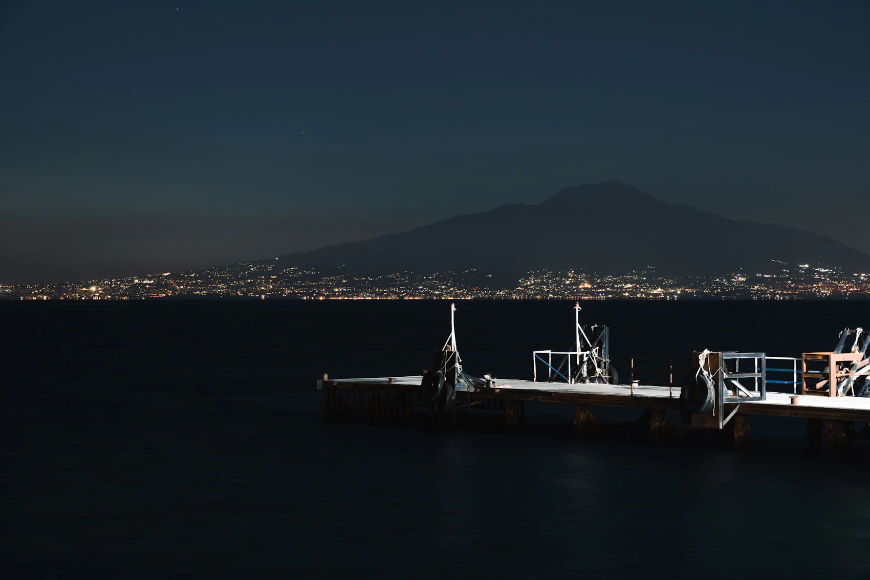 Vesuvius silhouetted above the lights of the Bay of Naples and a quiet night pier