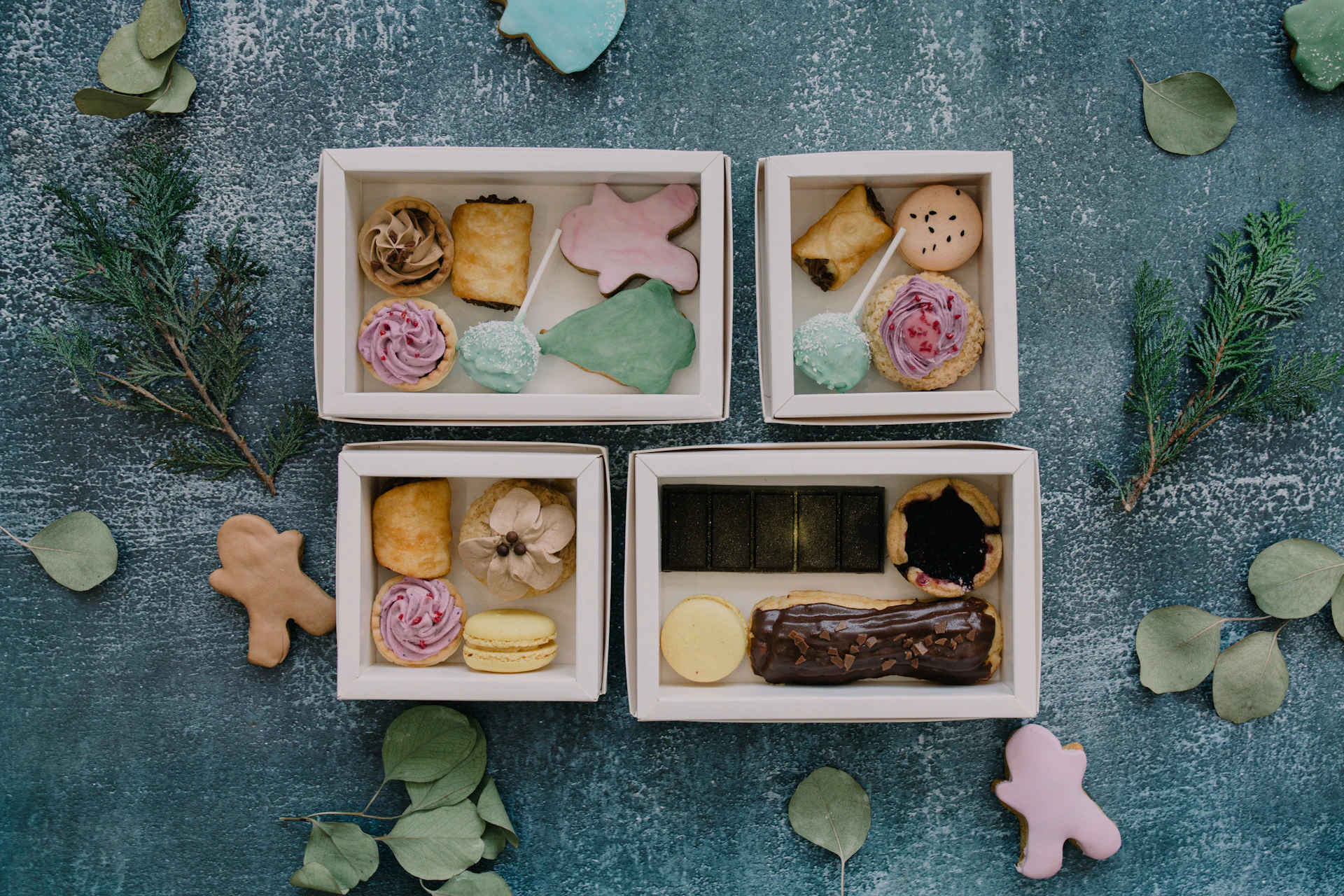 Four small boxes filled with different types of pastries